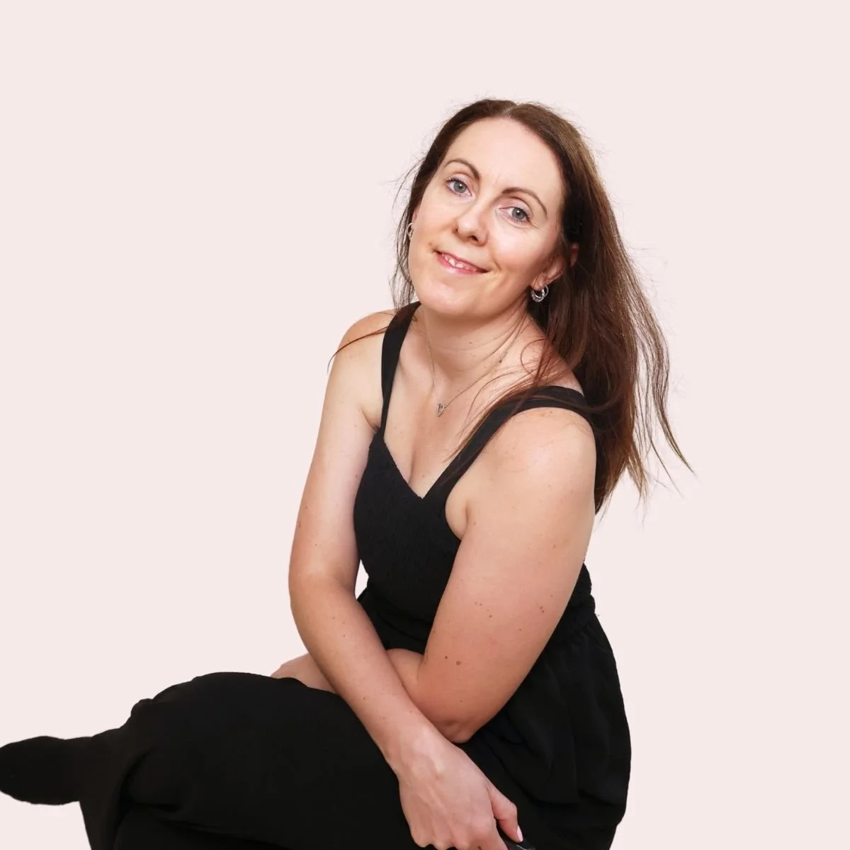Louise Laurie, digital marketing strategist and educator, smiling confidently in a black outfit against a soft pink background.