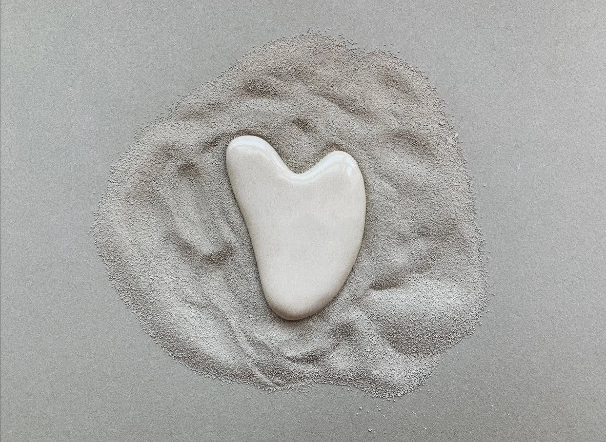 Piedra blanca en forma de corazón sobre arena gris