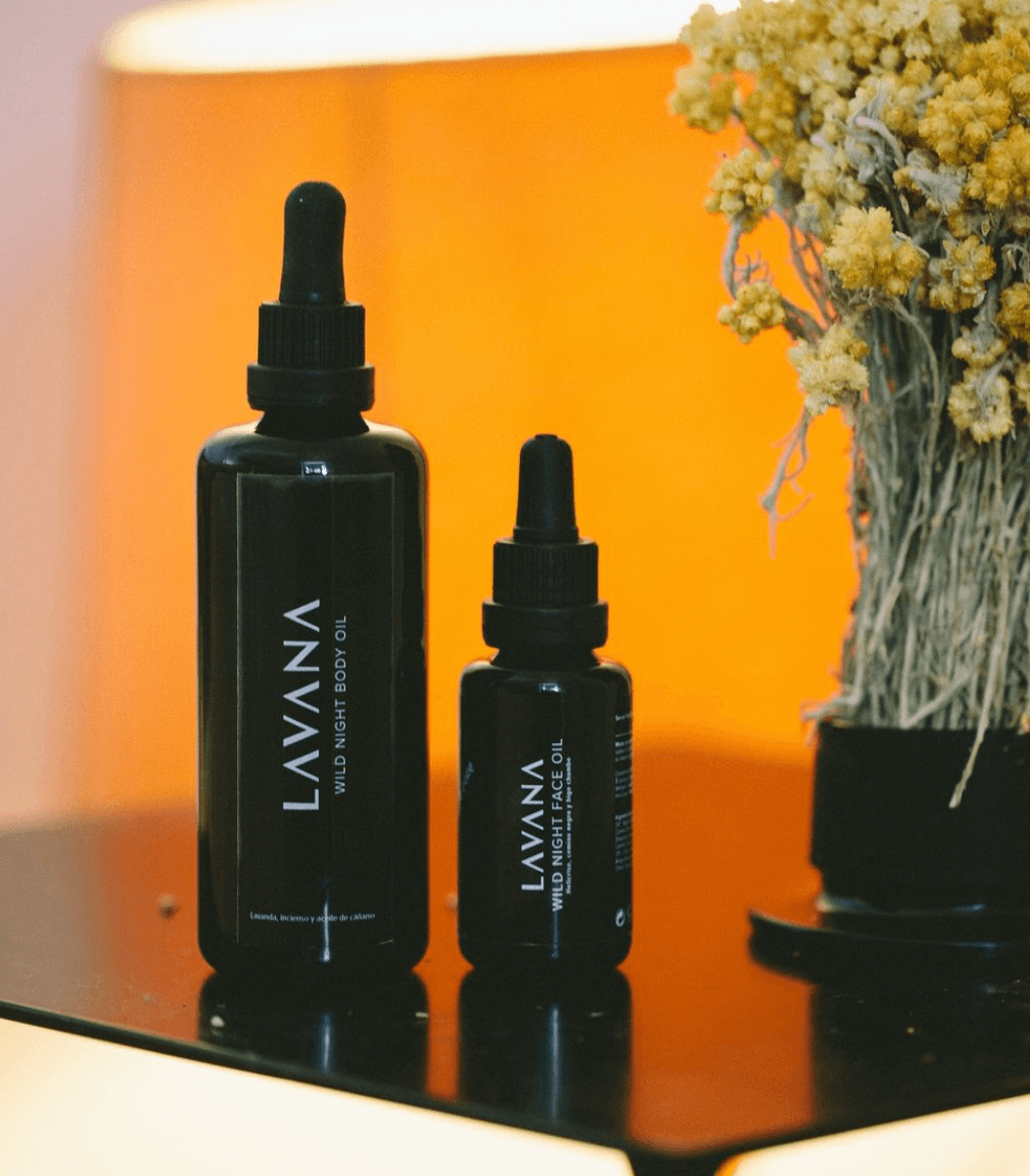 Botellas de aceite nocturno de la marca LAVVANA junto a un ramo de flores secas en una mesa.