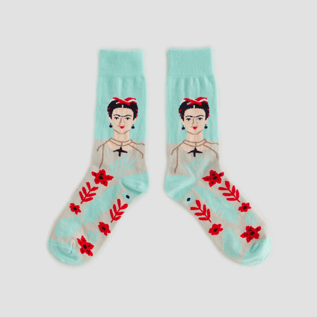 Par de calcetines con diseño de Frida Kahlo, con fondo de color aqua, en la parte superior un retrato de Frida Kahlo y en la parte inferior flores rojas y hojas junto a retratos de loros.