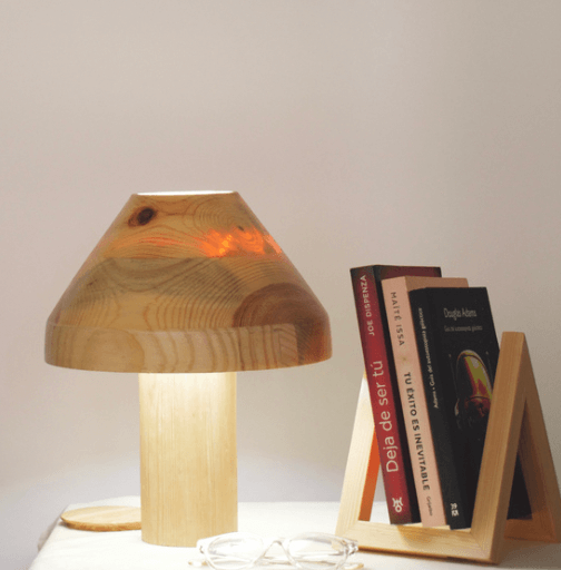 Lámpara de madera, libros de diferentes colores y un caballete de madera en una mesa