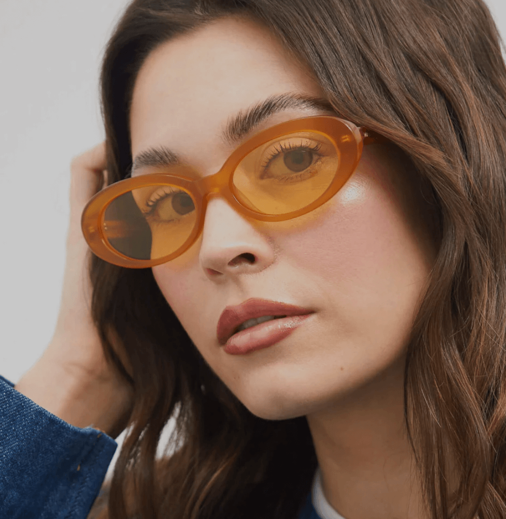 Mujer con gafas anaranjadas de forma ovalada y cabello castaño.