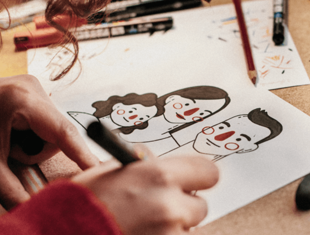 Persona dibujando una caricatura de tres personas en papel.