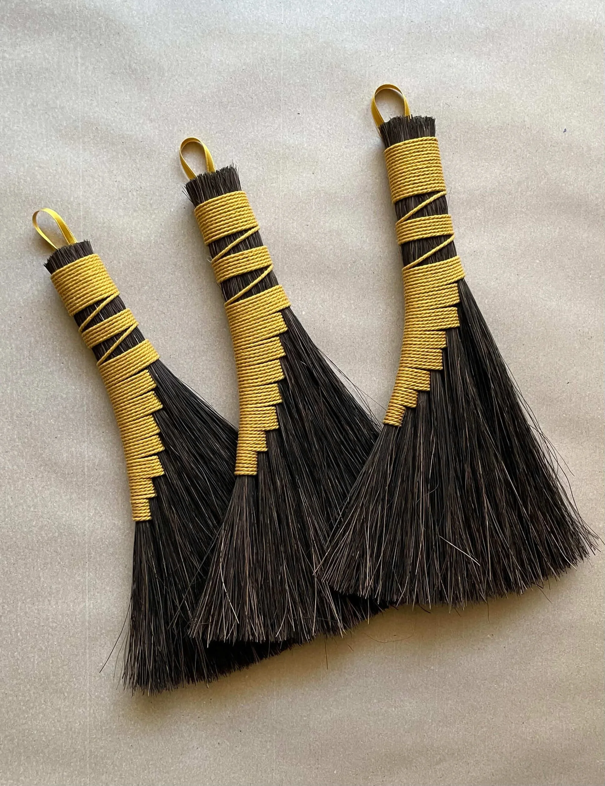 Tres manojos de cabello negro, con puntas cortas, envueltos y sujetos con cintas amarillas en la parte superior.