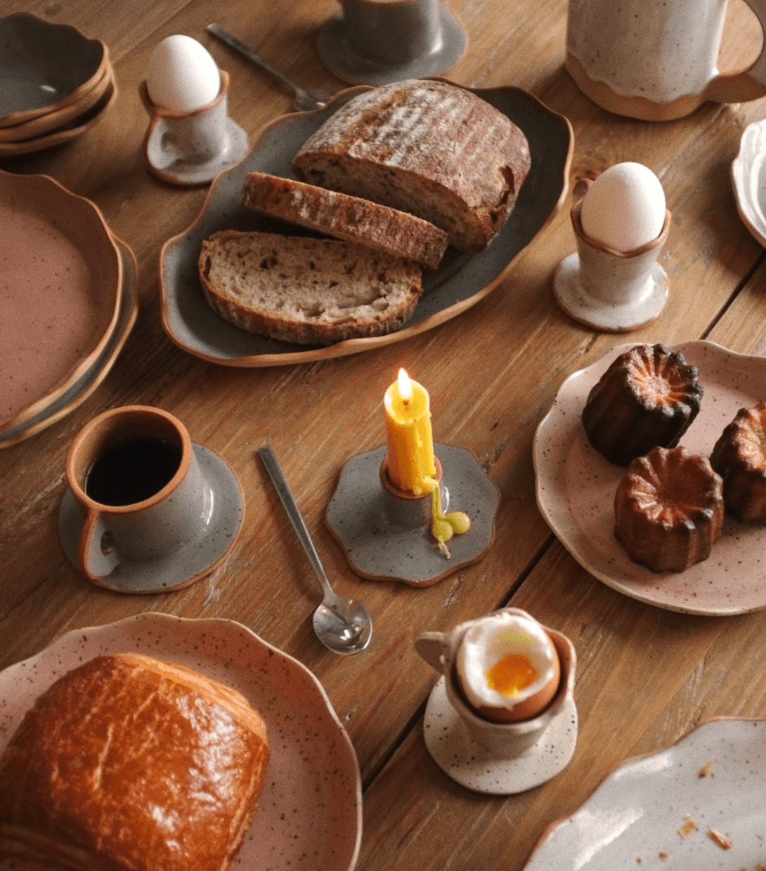 Desayuno con pan, huevos, canela, café, y diferentes panes y postres en la mesa.