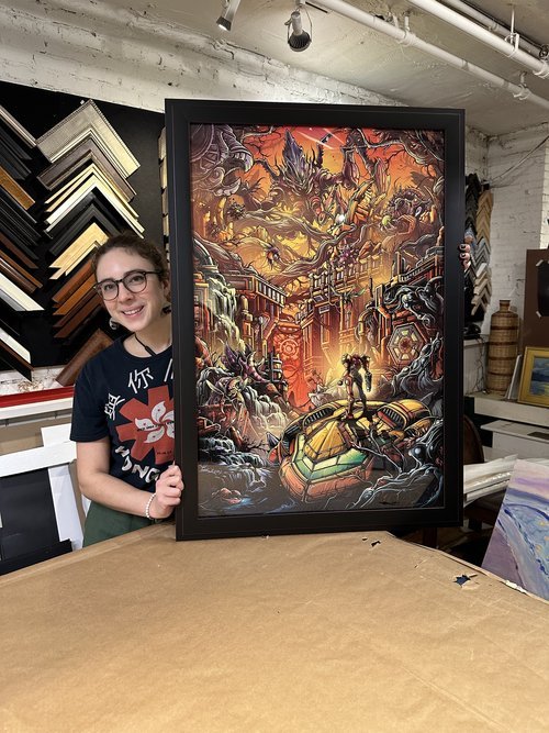 Tyler presenting a screen printed video game poster in a black frame with a subtle red line.