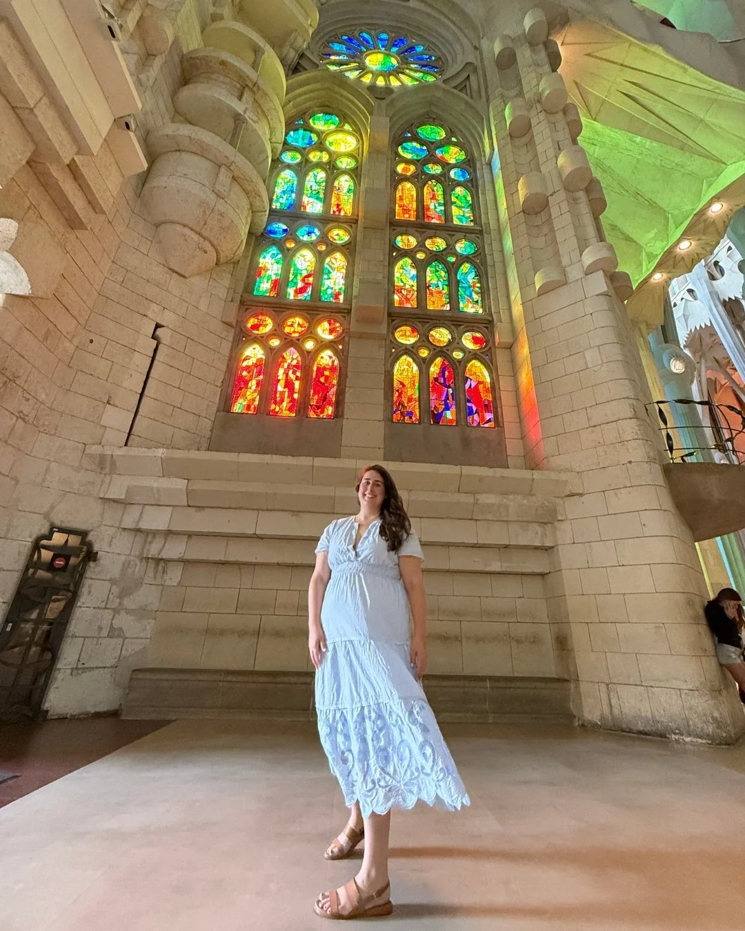 a woman stands under the stained glass in La Sagrada Família