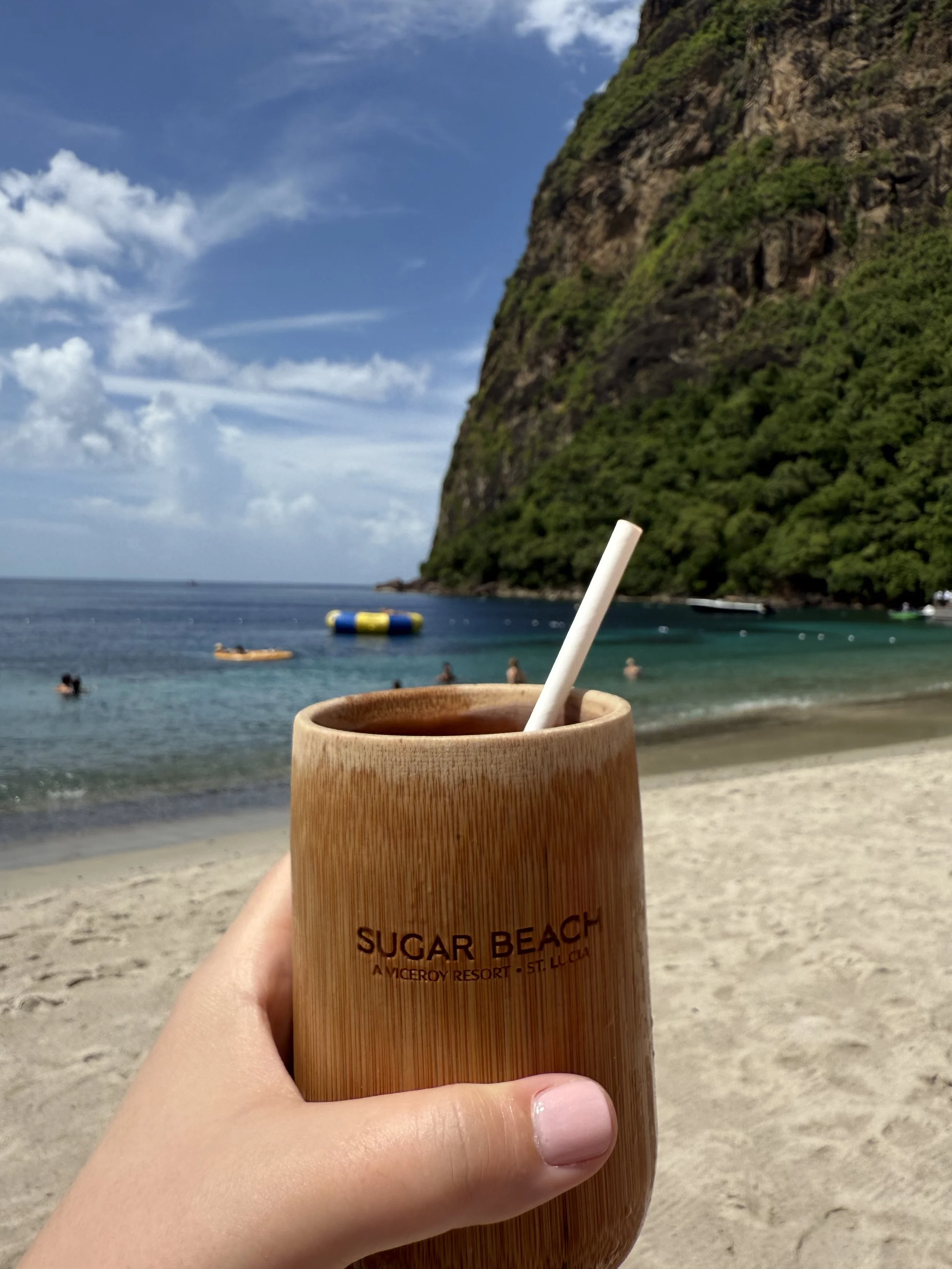 Holding a sugar beach cup at the edge of the beach with the Pitons in the background