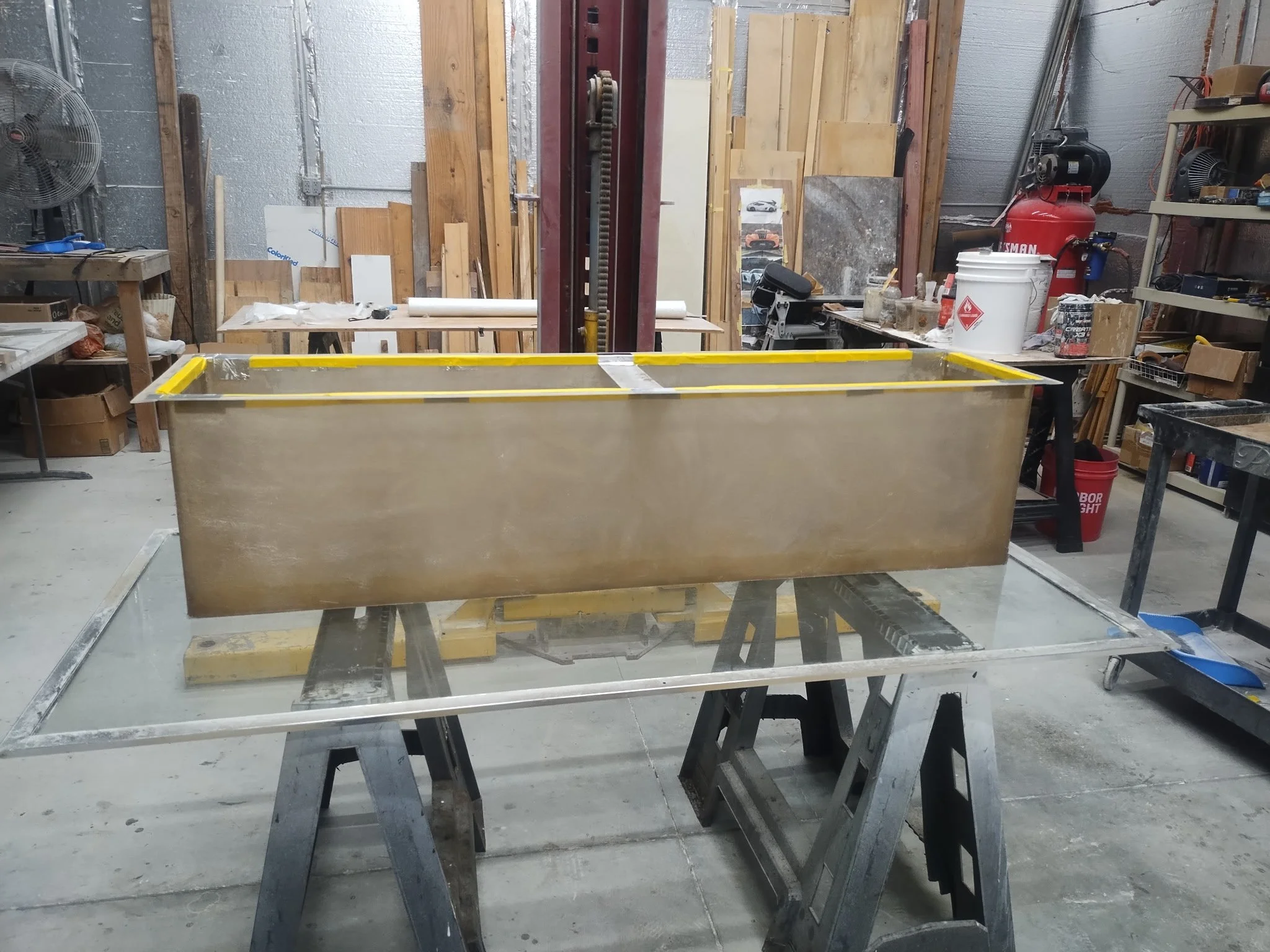 Workshop or construction area with worktable, tools, wooden panels, and equipment.
