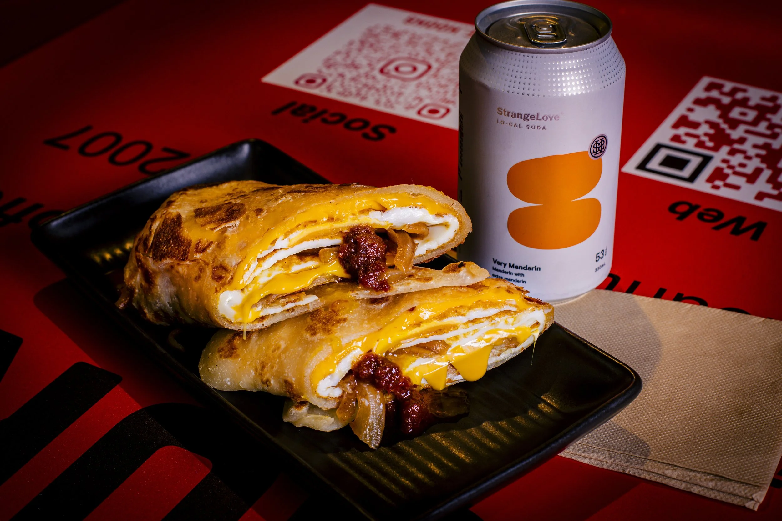 Pacific breakfast roti wrap with grilled eggs, cheddar and sambal, and a StrangeLove Very Mandarin soda, at Kafe Kooks, Ultimo
