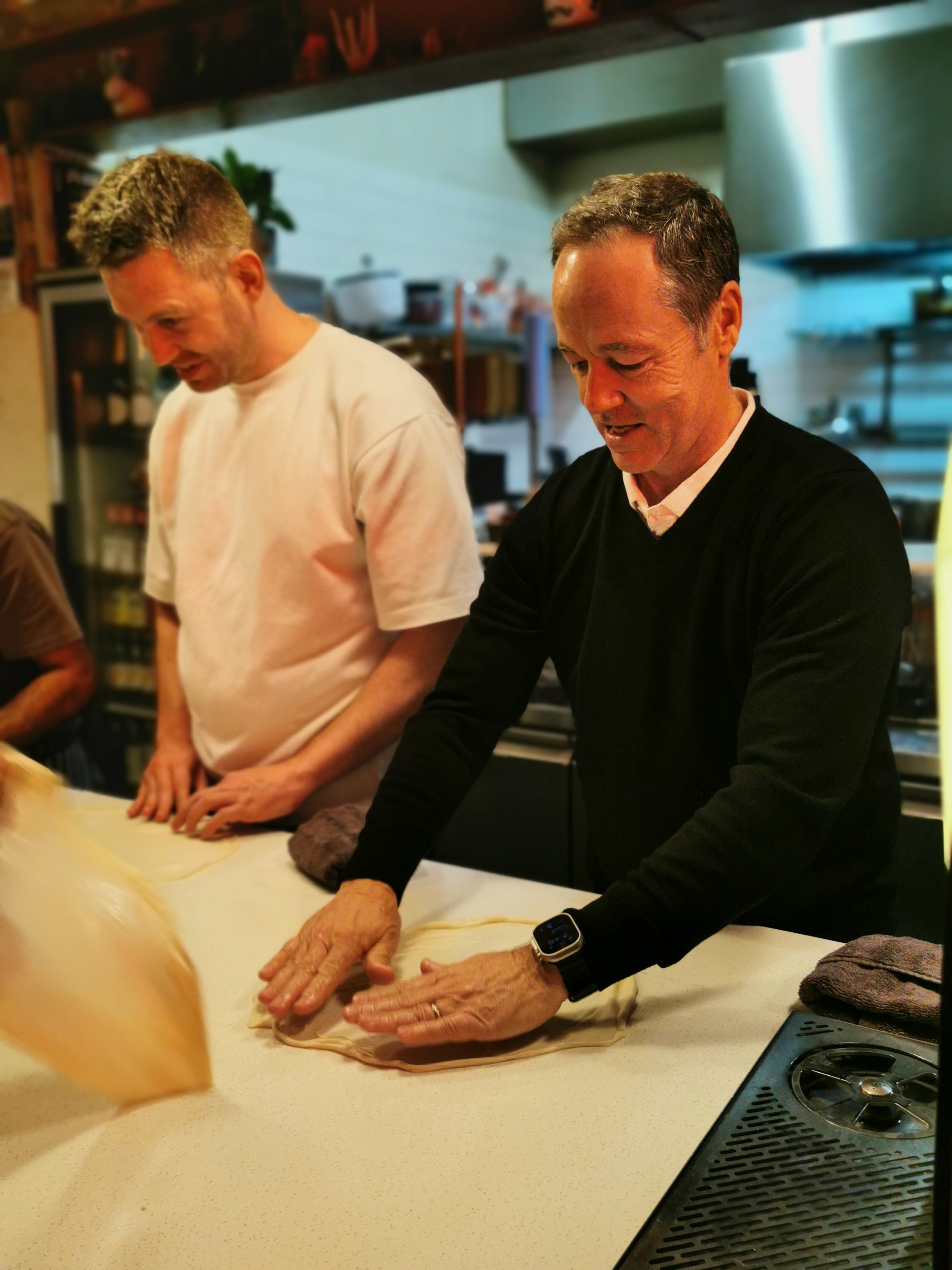 Hands stretching roti dough over the bench at Kafe Kooks