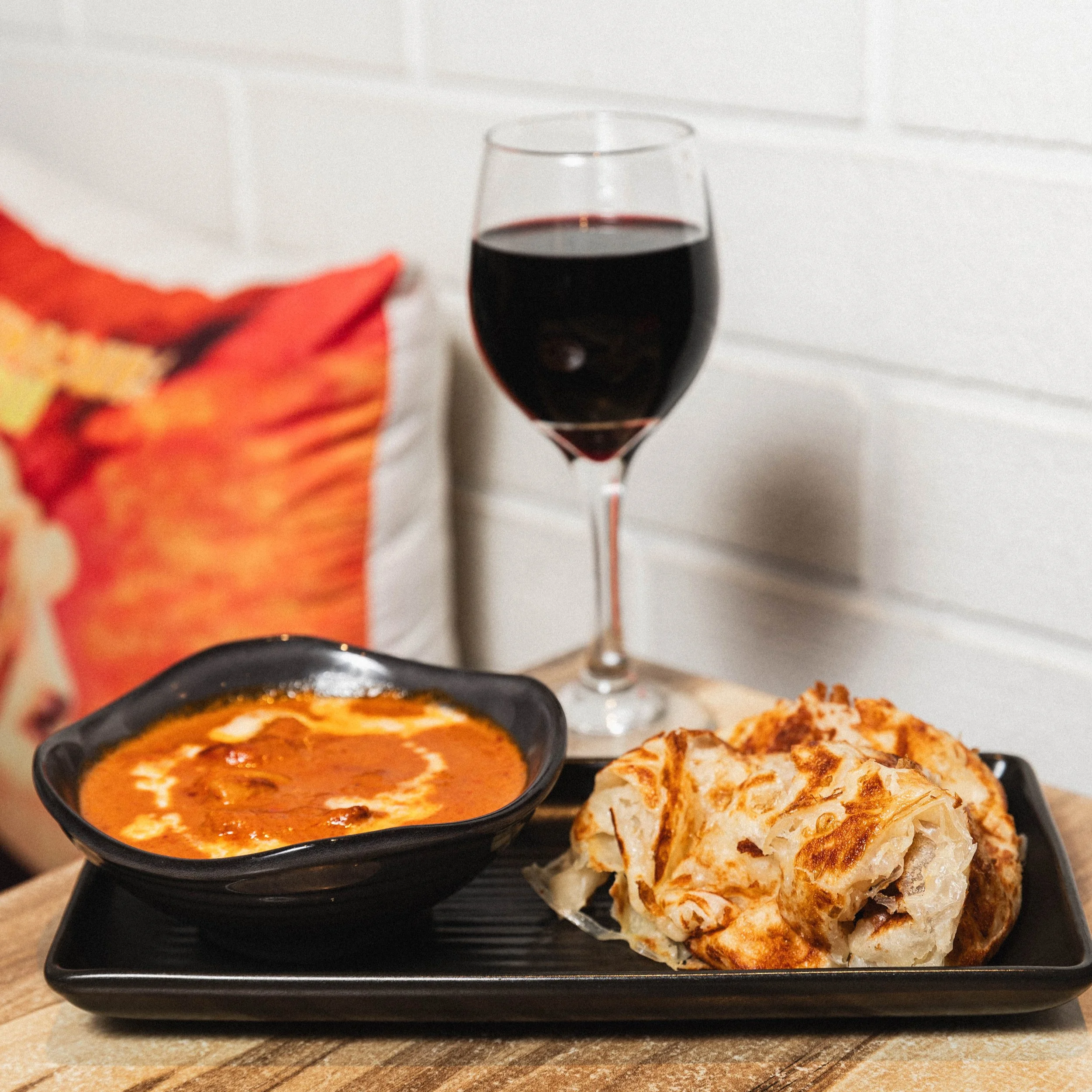 Creamy butter chicken curry with roti paratha and a glass of Pinot Noir, at Kafe Kooks, Ultimo
