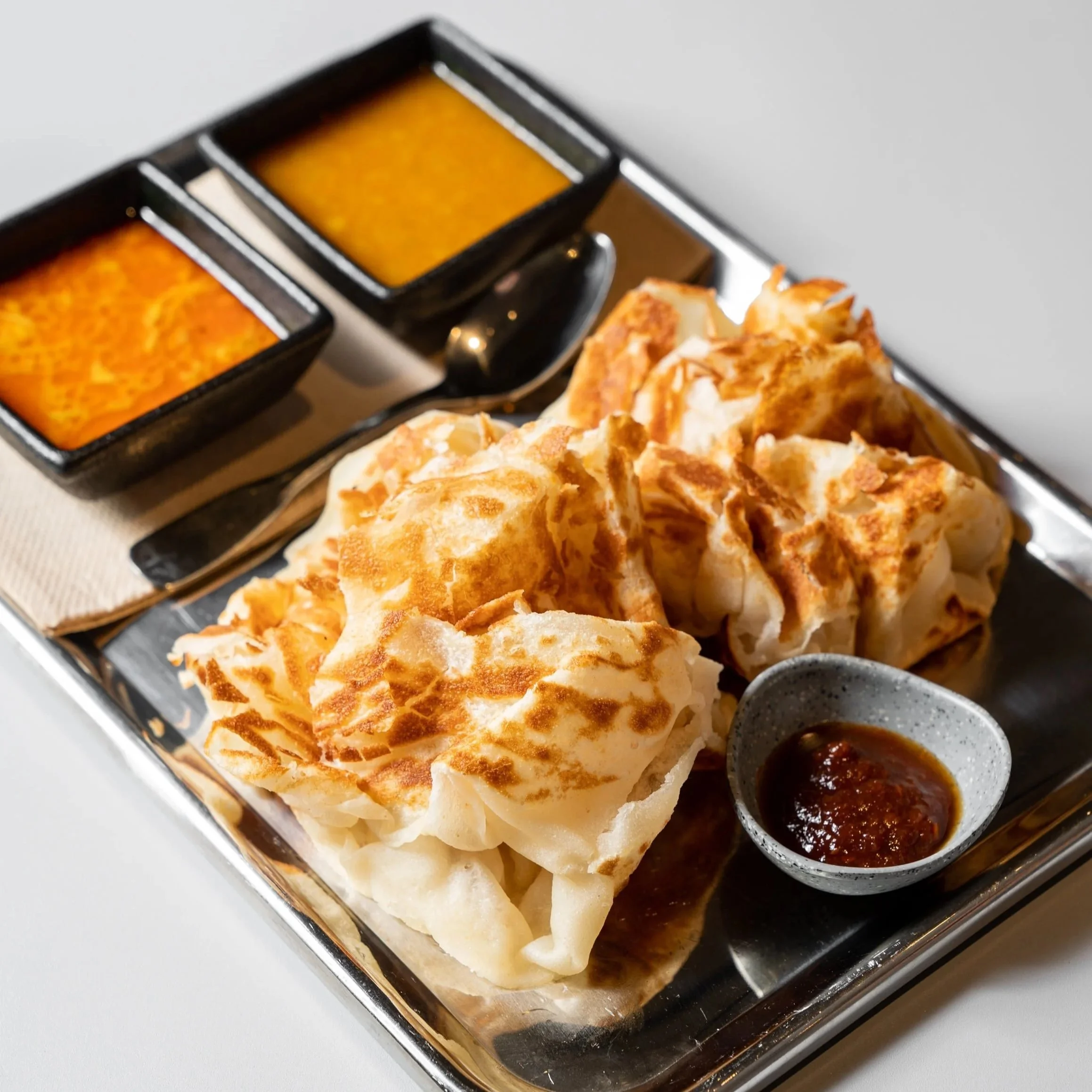 Roti canai, two roti paratha with chicken curry, vegetable curry and house-made sambal, at Kafe Kooks, Ultimo