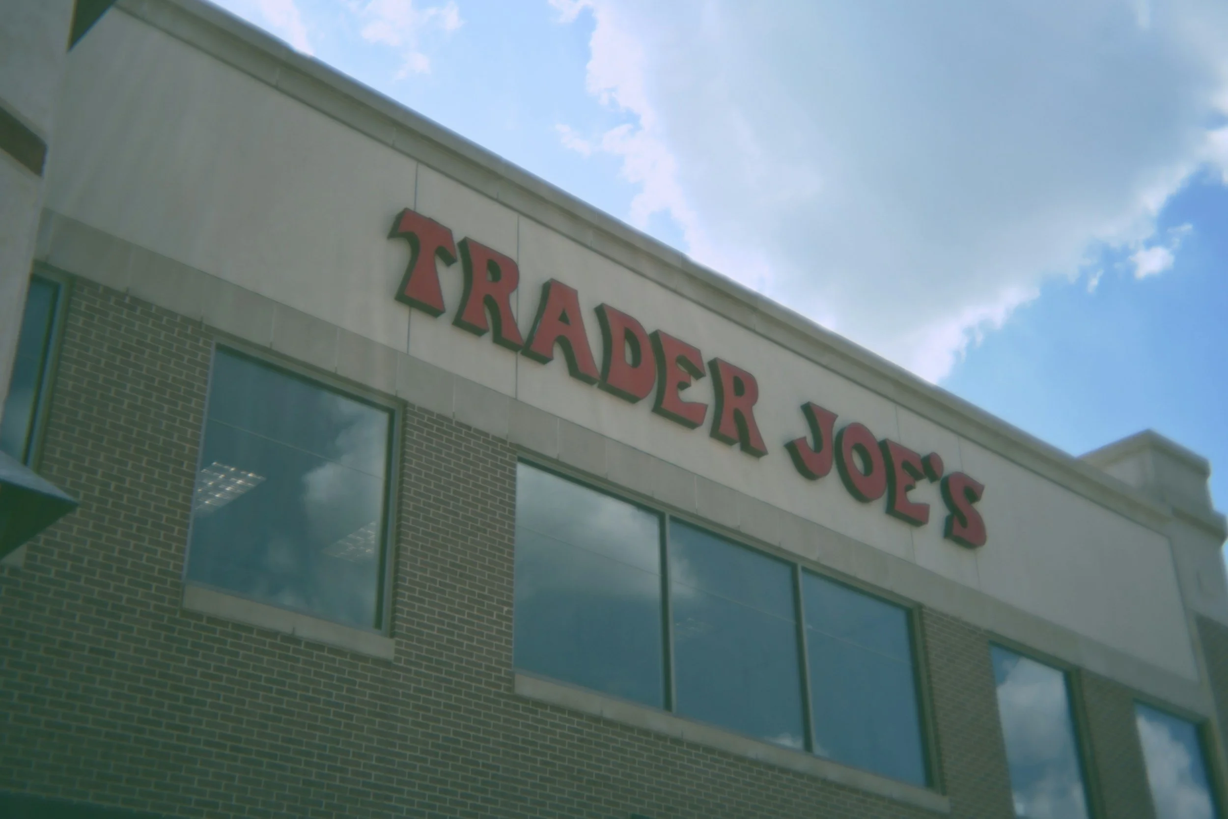 The exterior of Trader Joe's store with large windows and red signage on the building facade.