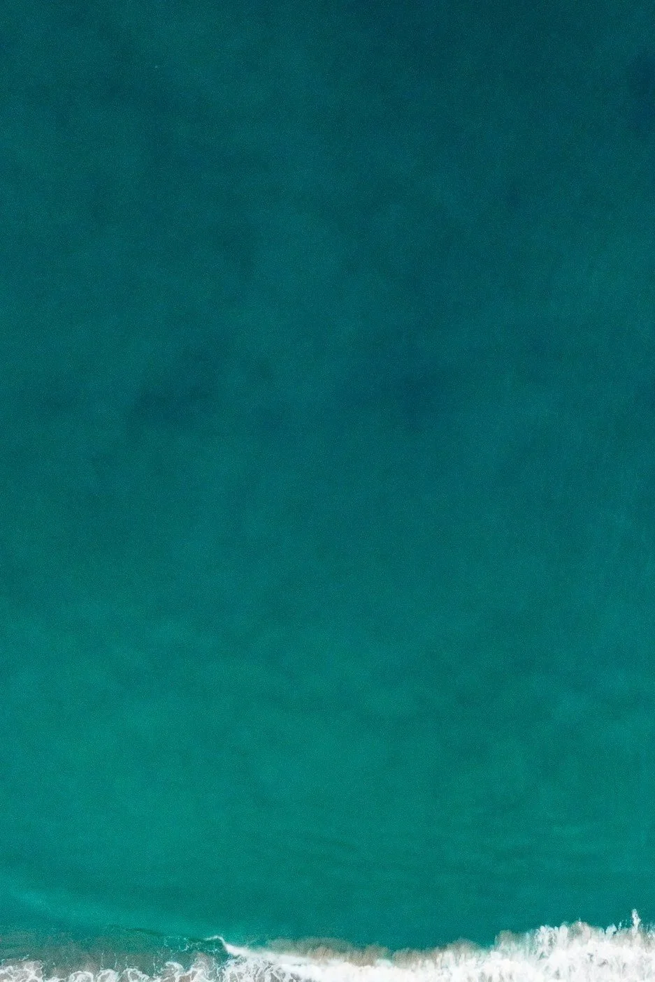 Aerial view of ocean with waves near shoreline