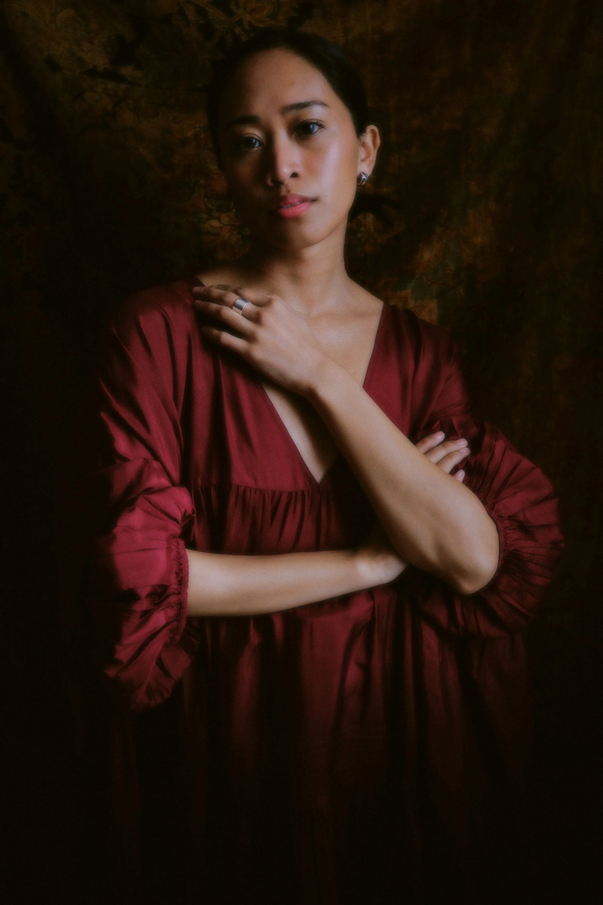 woman in a red shirt, with brown hair and arms crossed