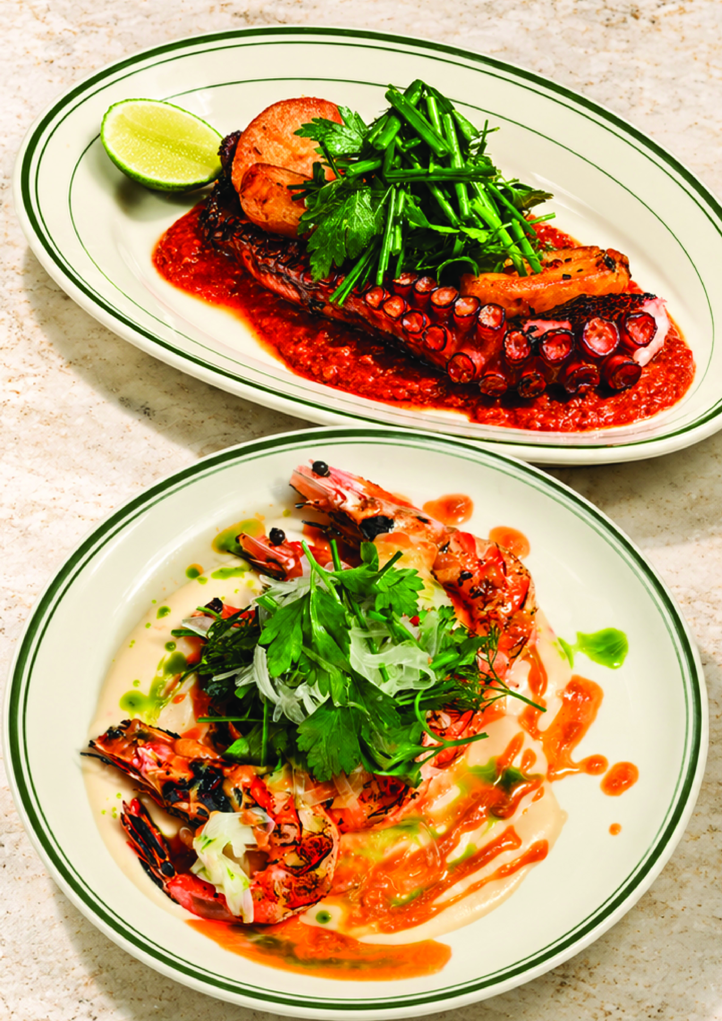 Plate of grilled octopus with green vegetables, lime wedge, and garnishes