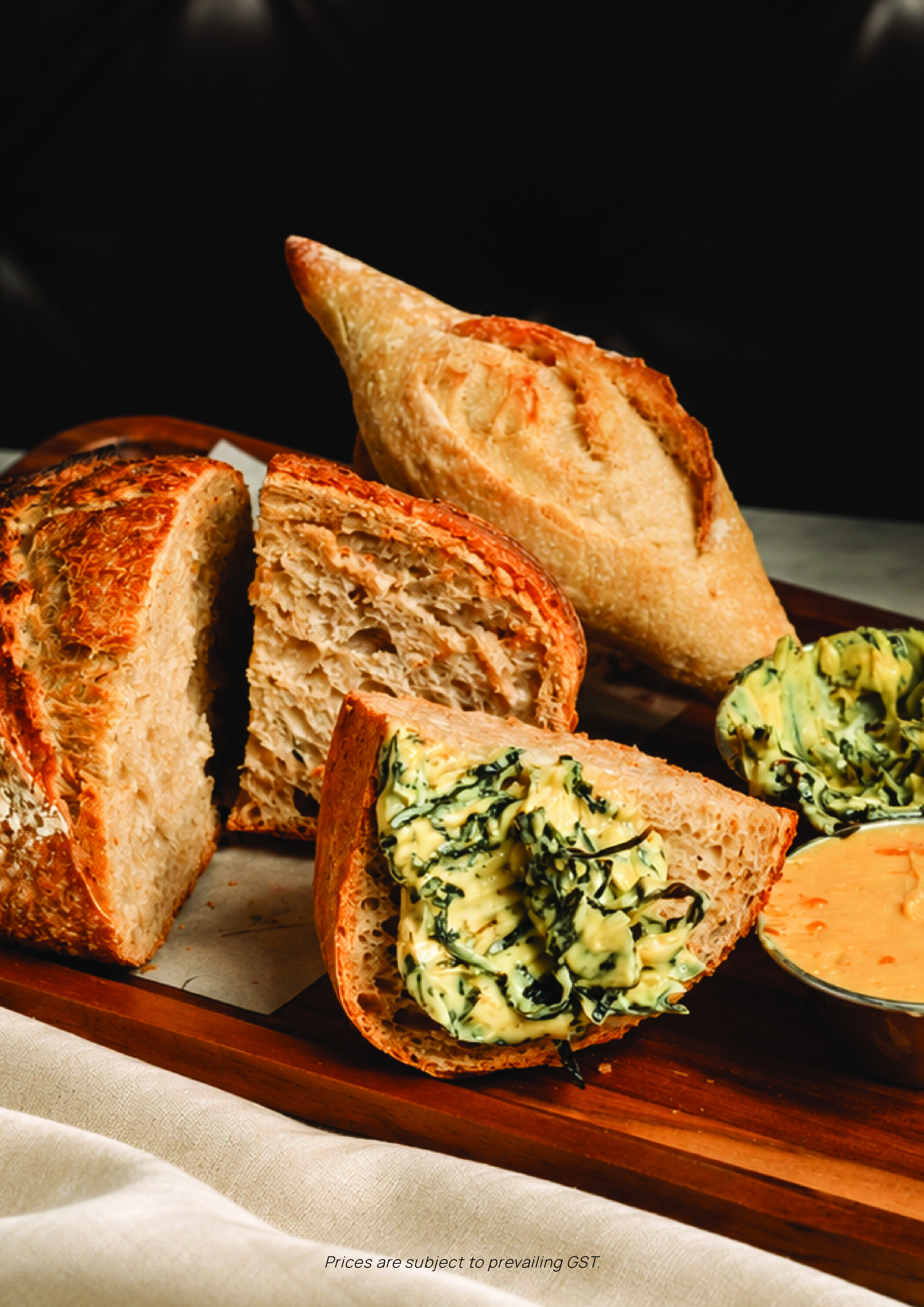 Assorted bread with butter and spread, displayed on a wooden platter.