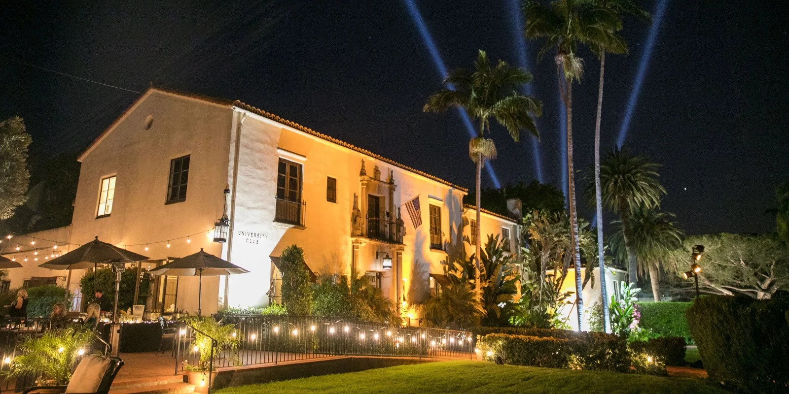 Riviera Mansion in Santa Barbara illuminated at night, with palm trees and garden lights