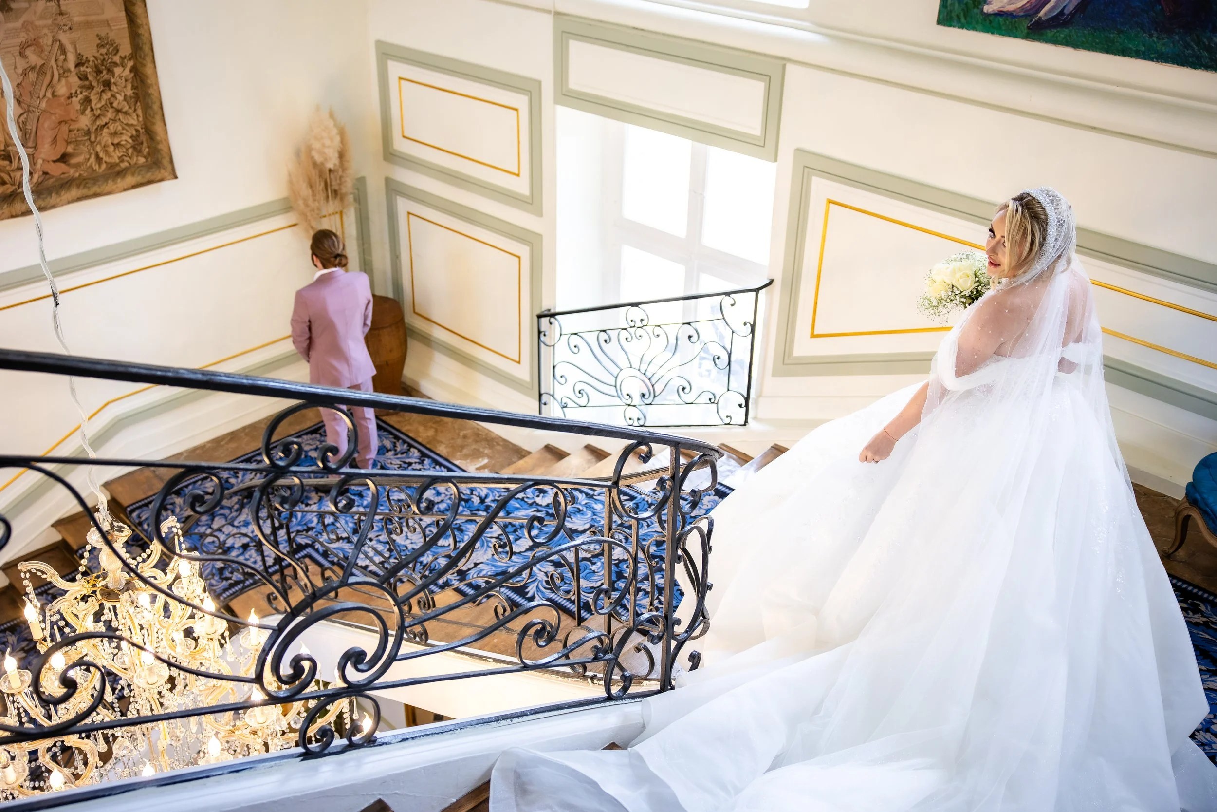 Moment du First Look au Château d’Aveny dans le Vexin : la mariée descend l’escalier pour retrouver son futur mari lors d’un mariage chic et haut de gamme – photo Stéphane Bourgeon Photography