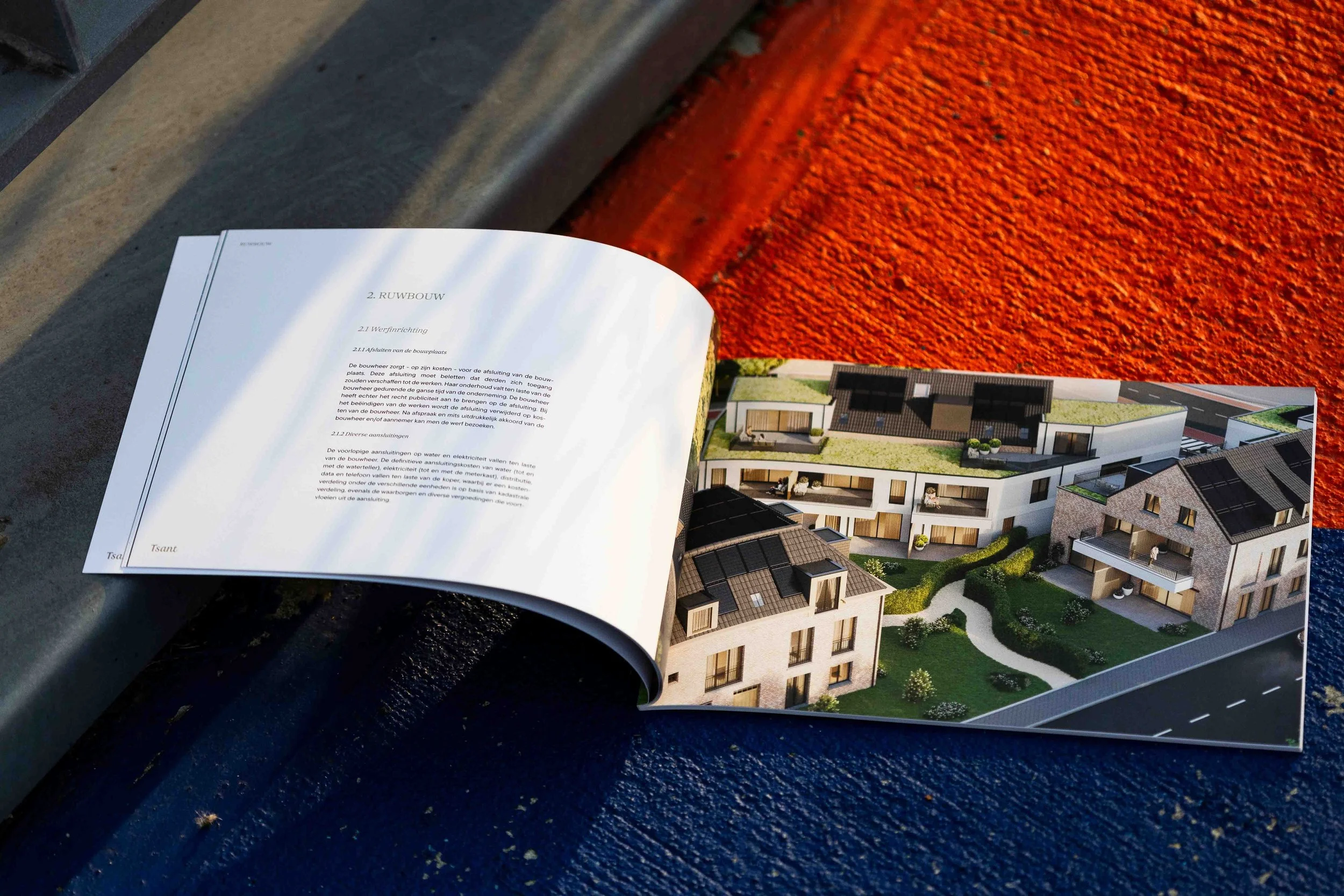 Open building plan magazine showing a 3D architectural rendering of modern apartment buildings and a page with text in a foreign language.