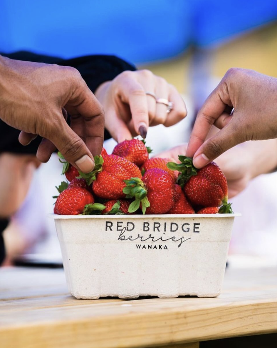 Friends sharing strawberries from a punnet.