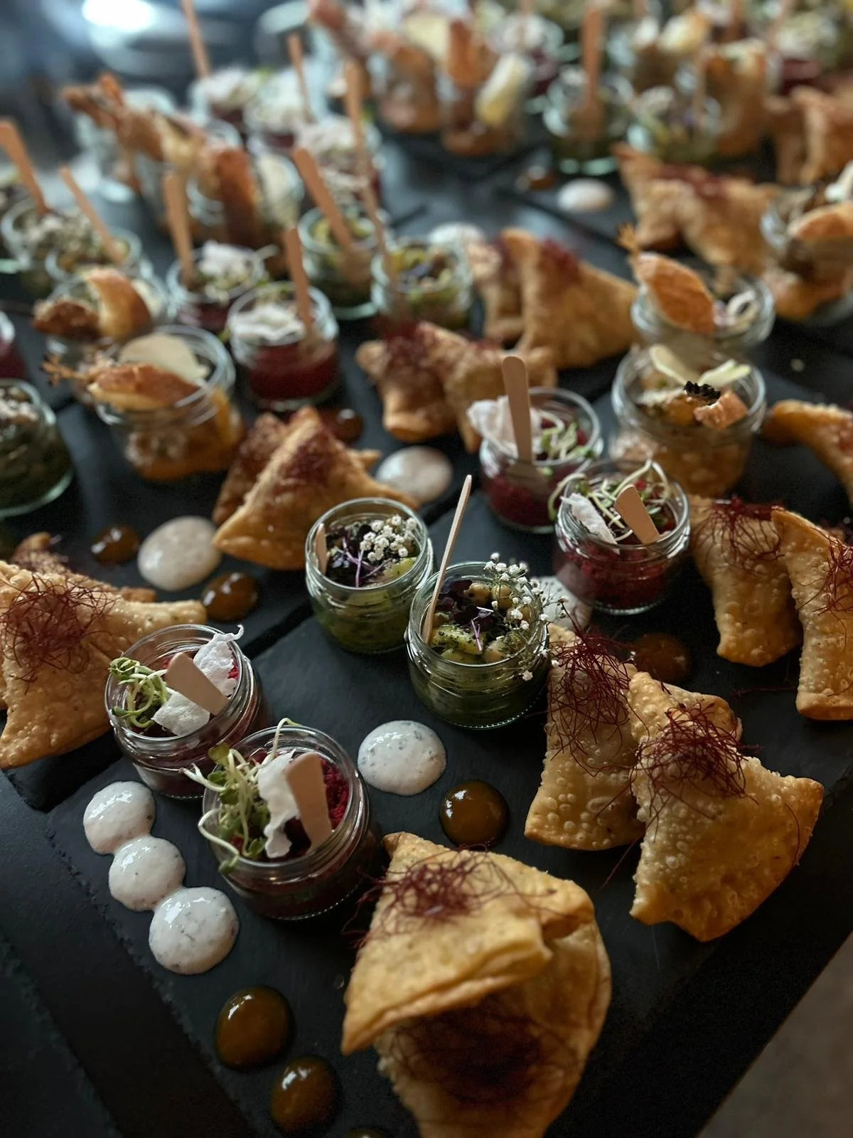 Verschiedene appetitliche Häppchen und Vorspeisen auf einer schwarzen Platte, Catering Buffet Wiesbaden