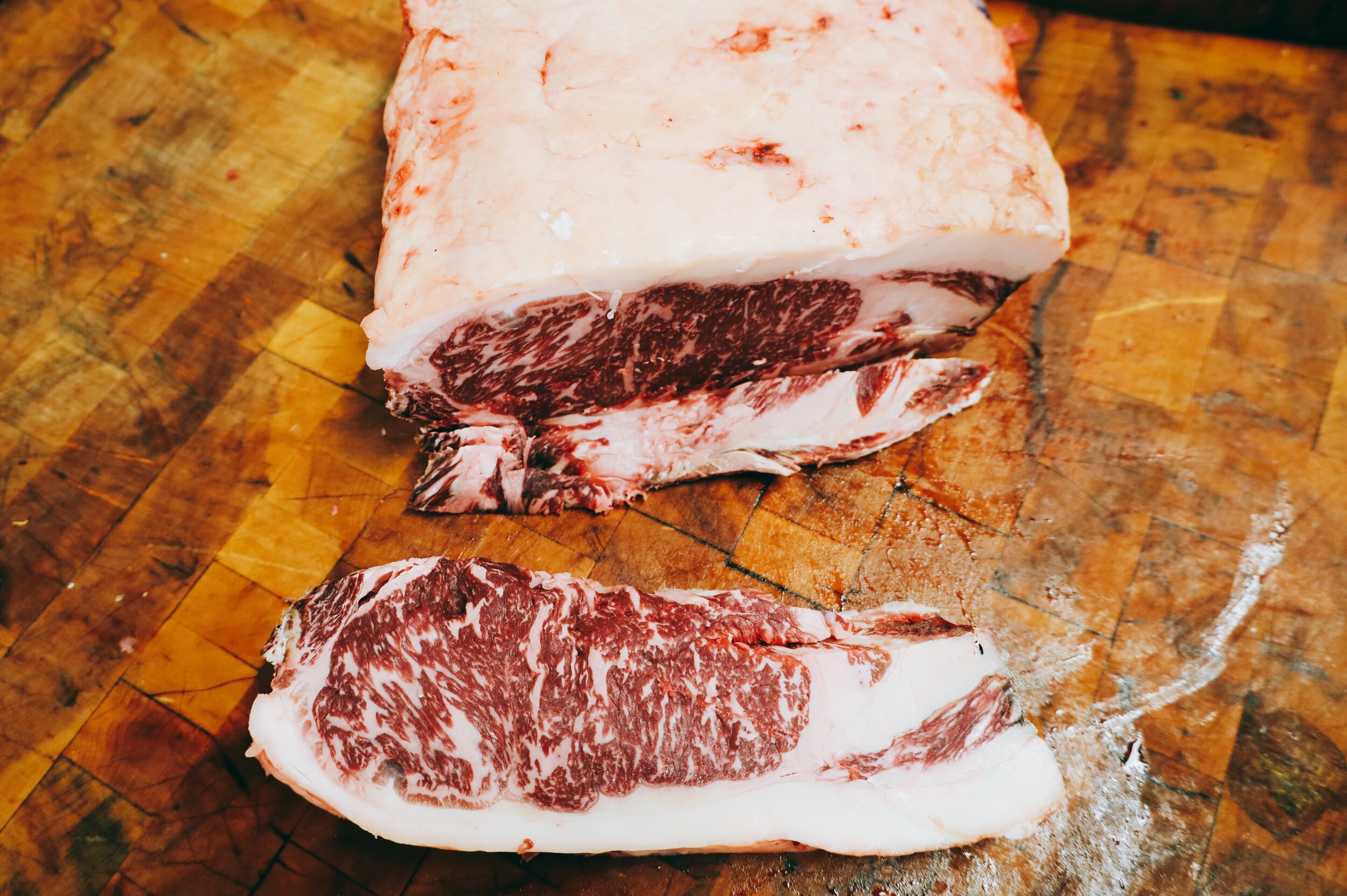 Wagyu steak with marbling on a wooden cutting board.