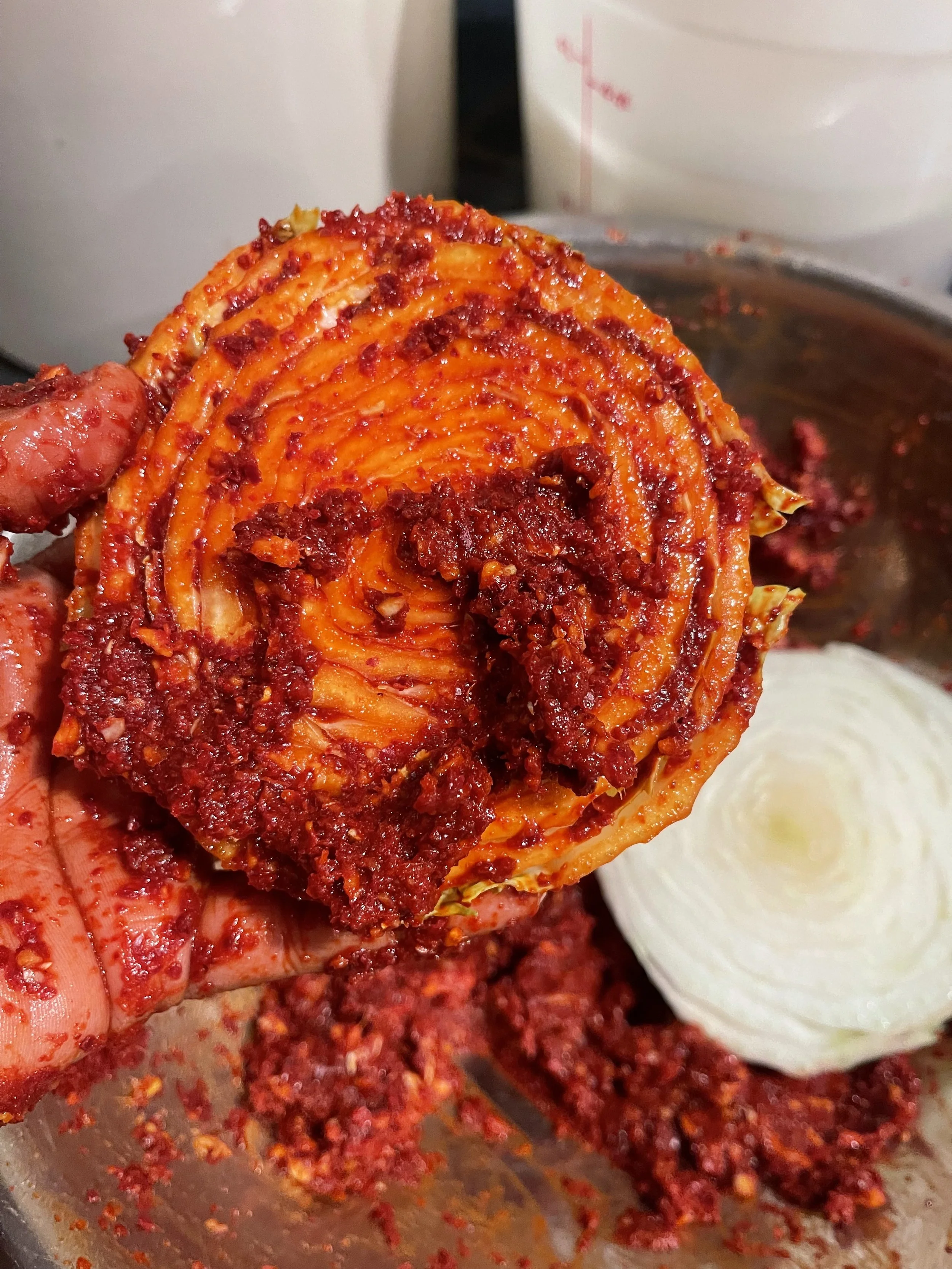 hand holding scraps of napa with kimchi paste applied wild fermentation
