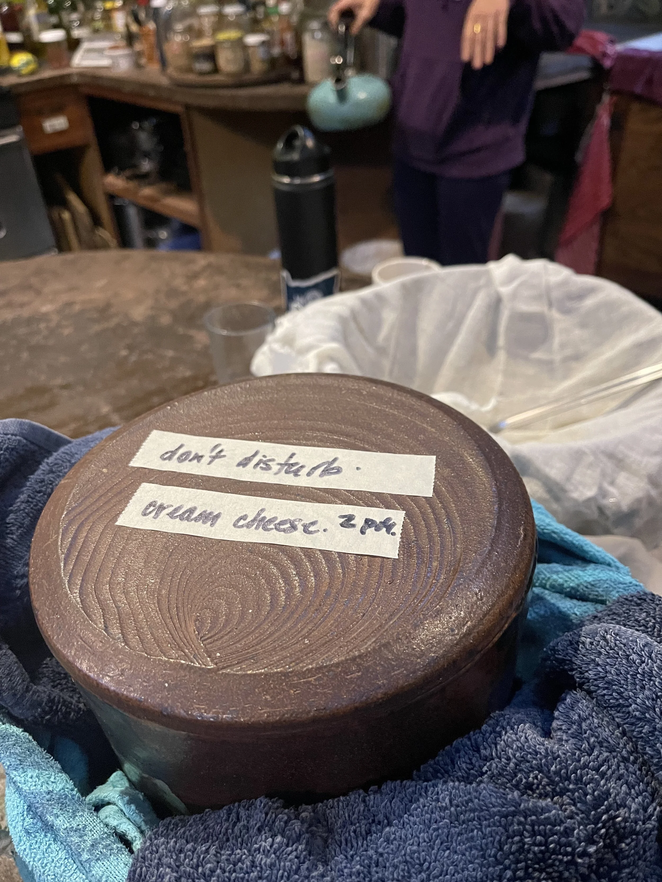 lidded stoneware crock wrapped in towels and labeled cream cheese, do not disturb