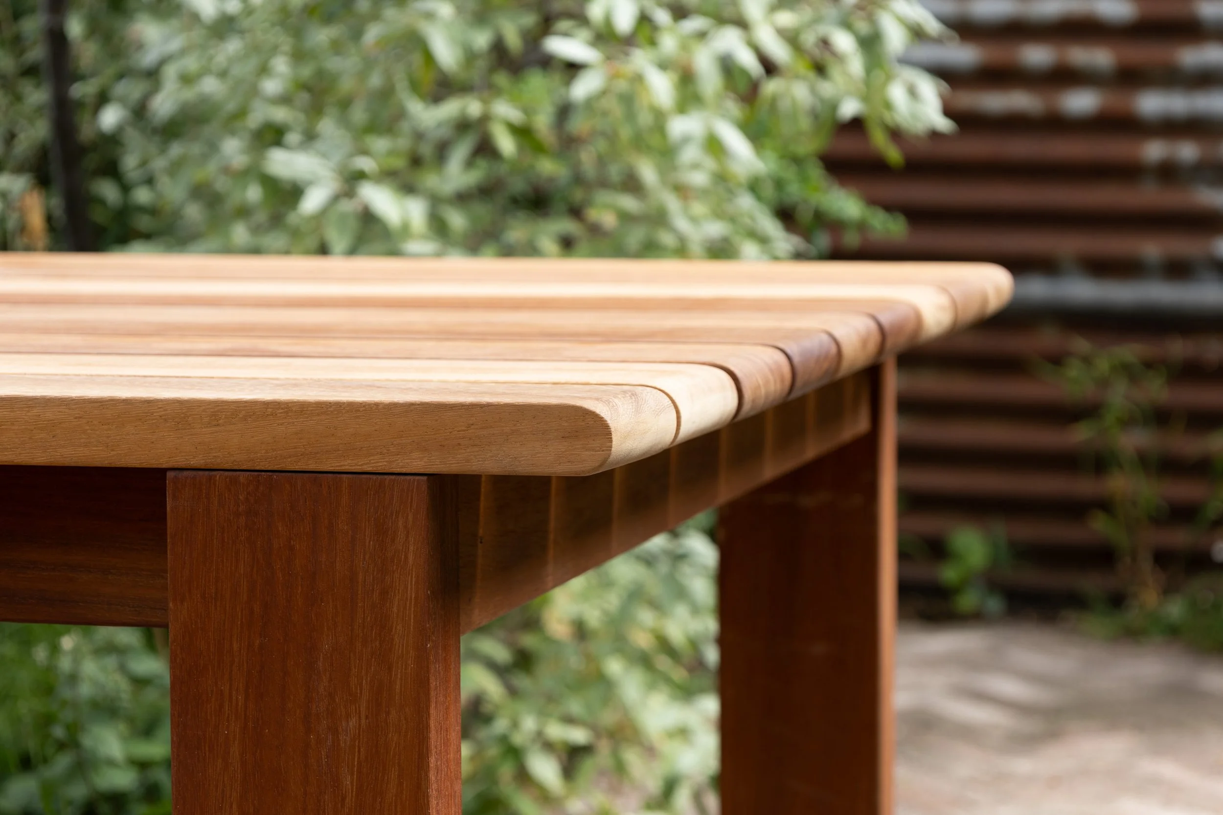 Close-up of a wooden outdoor table with a blurred garden background.