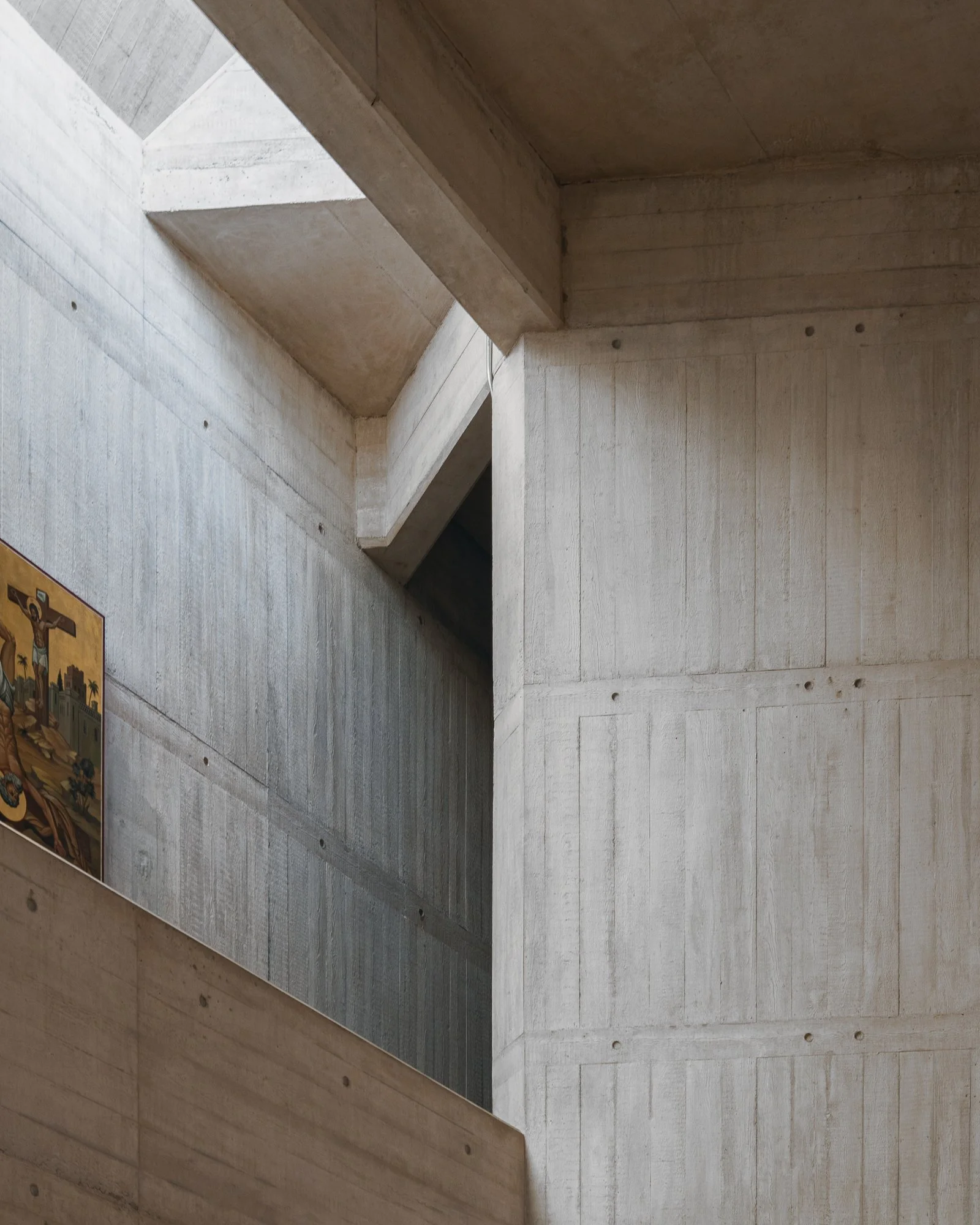 Interior view of modern architectural building with concrete walls and ceiling, featuring clean lines and geometric shapes.