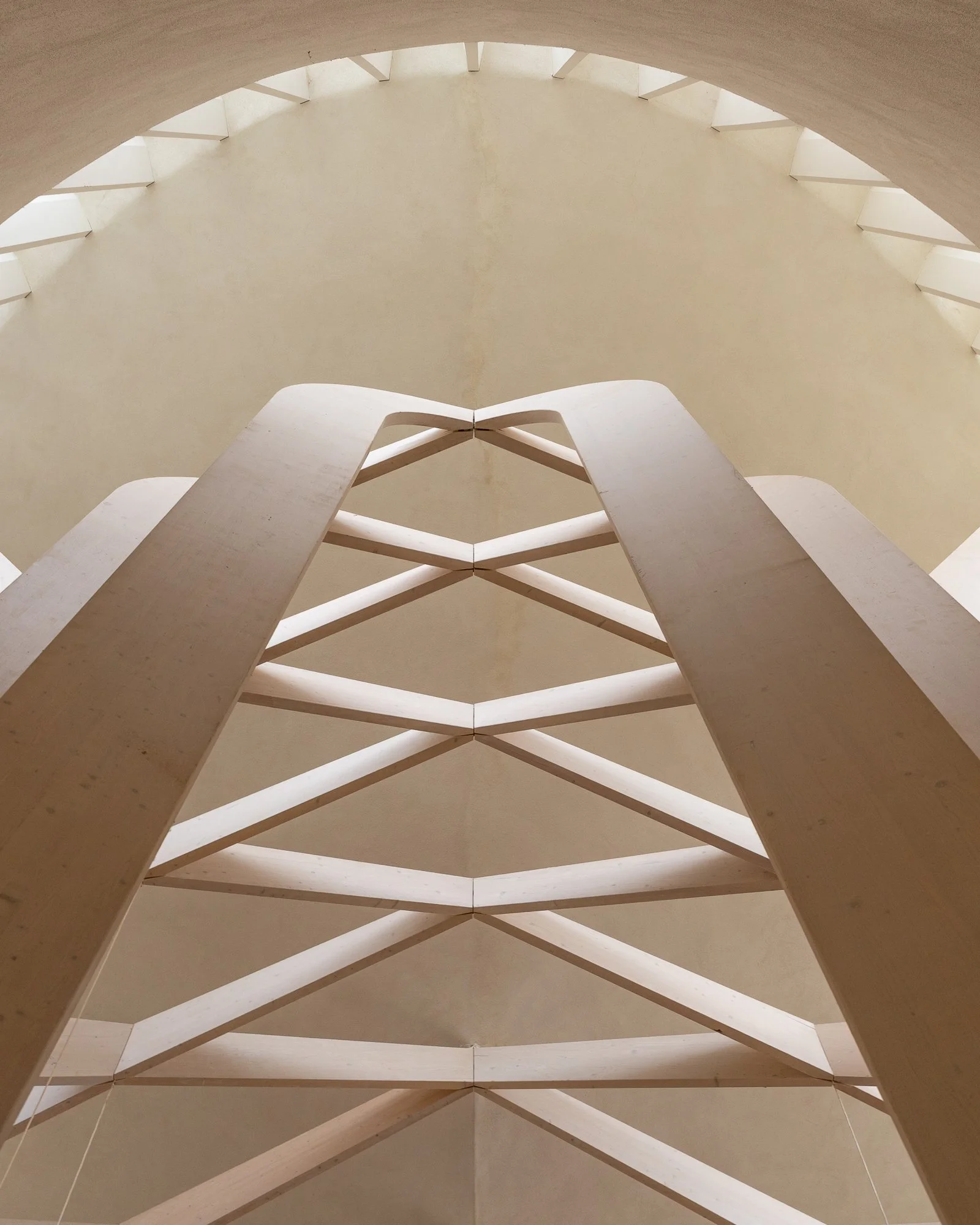 Interior view of a spiral staircase from below, showing beige steps and the circular pattern of the staircase.