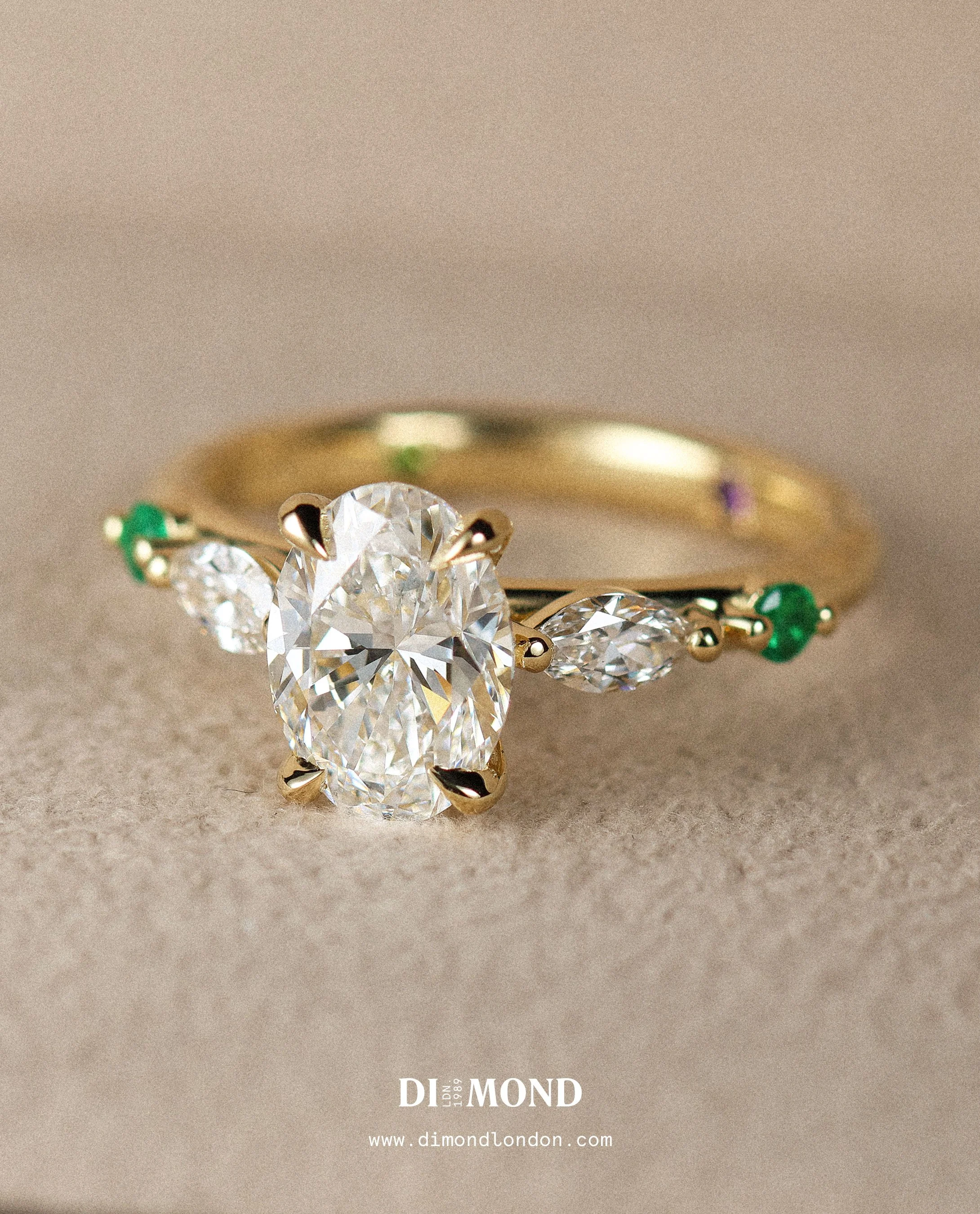 Oval cut diamond on a decorative marquise and emerald band.