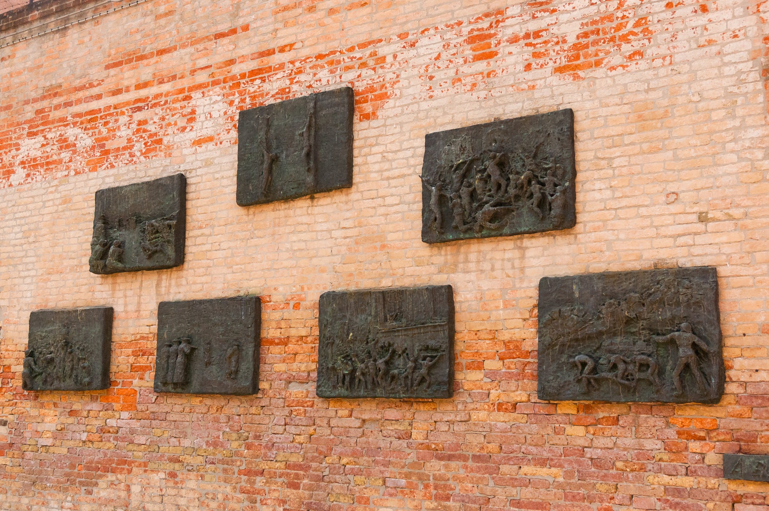 brick wall with plaques depicting the terrors of the holocaust