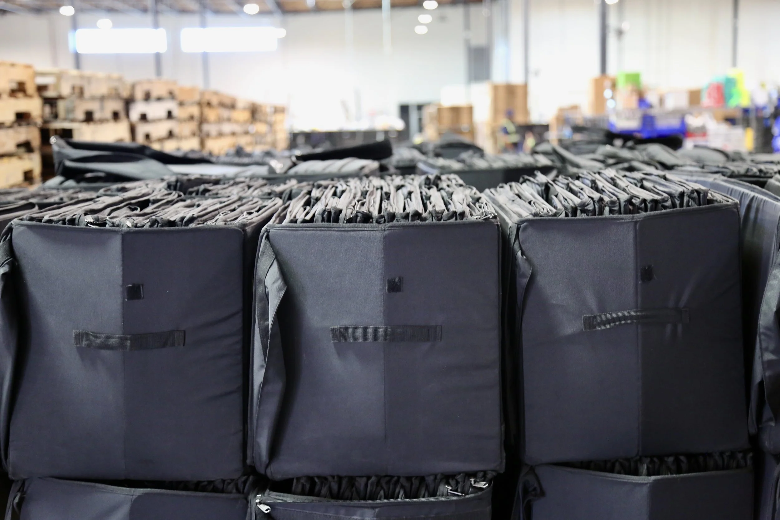 Stacks of black tote bags in a warehouse or storage facility.