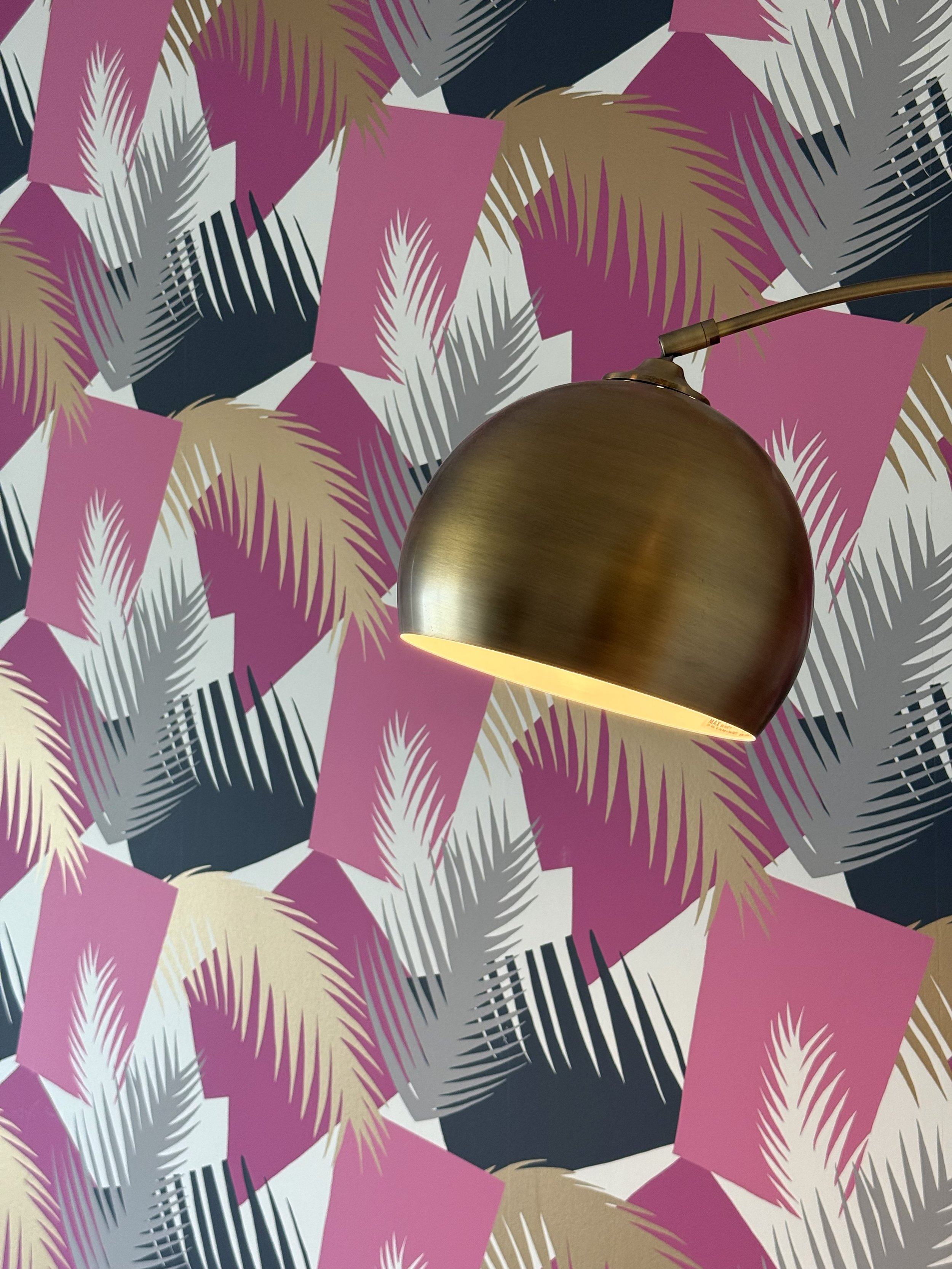 A vibrant family room in a luxury Edgewater Miami penthouse condo embraces bold contemporary interior design with a playful yet sophisticated aesthetic overlooking the sunset terrace. A striking designer wallpaper featuring graphic and colorful palm 