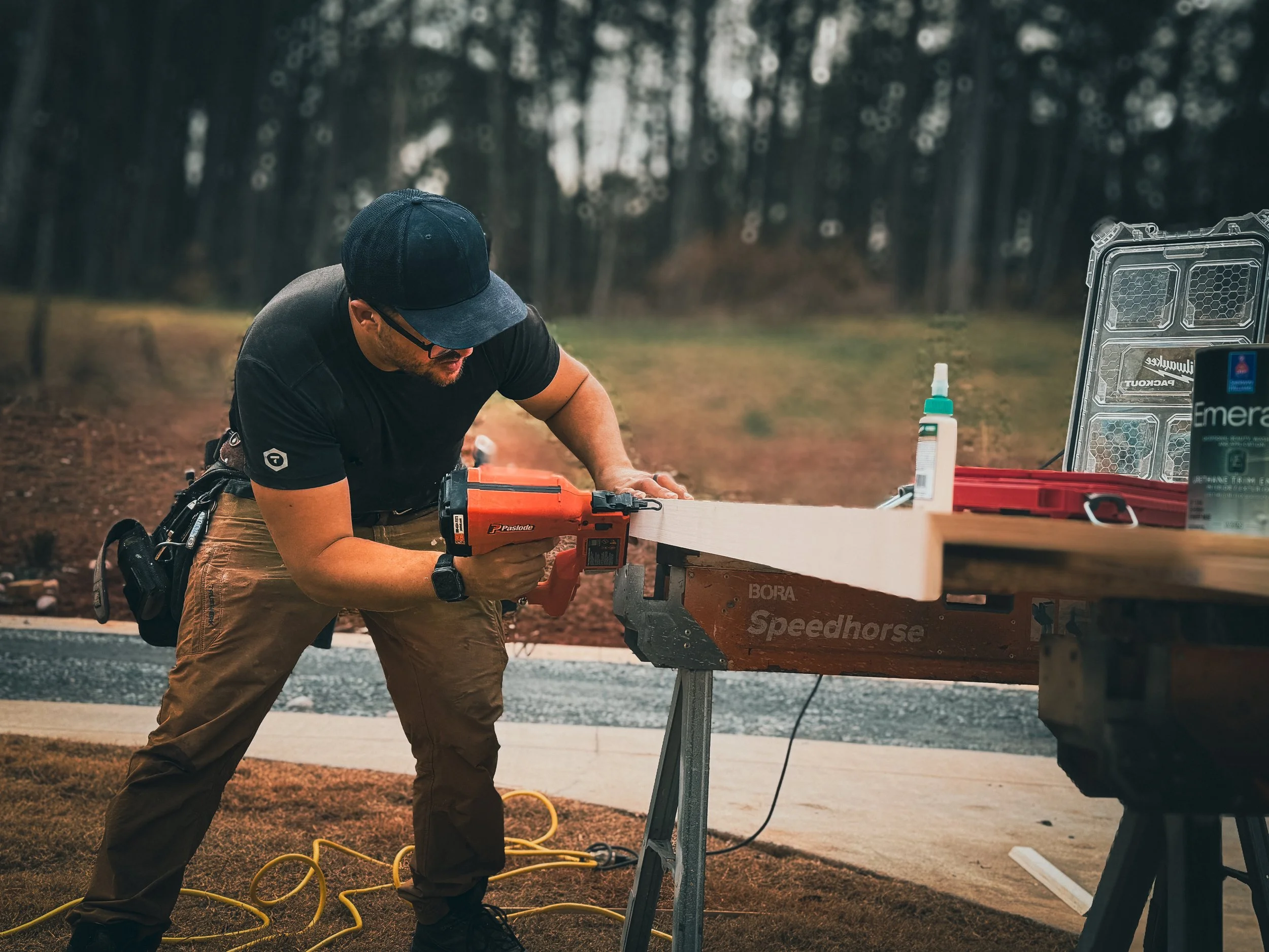Athens GA handyman performing residential carpentry work, fastening wood trim with a nail gun while building a custom countertop outdoors.