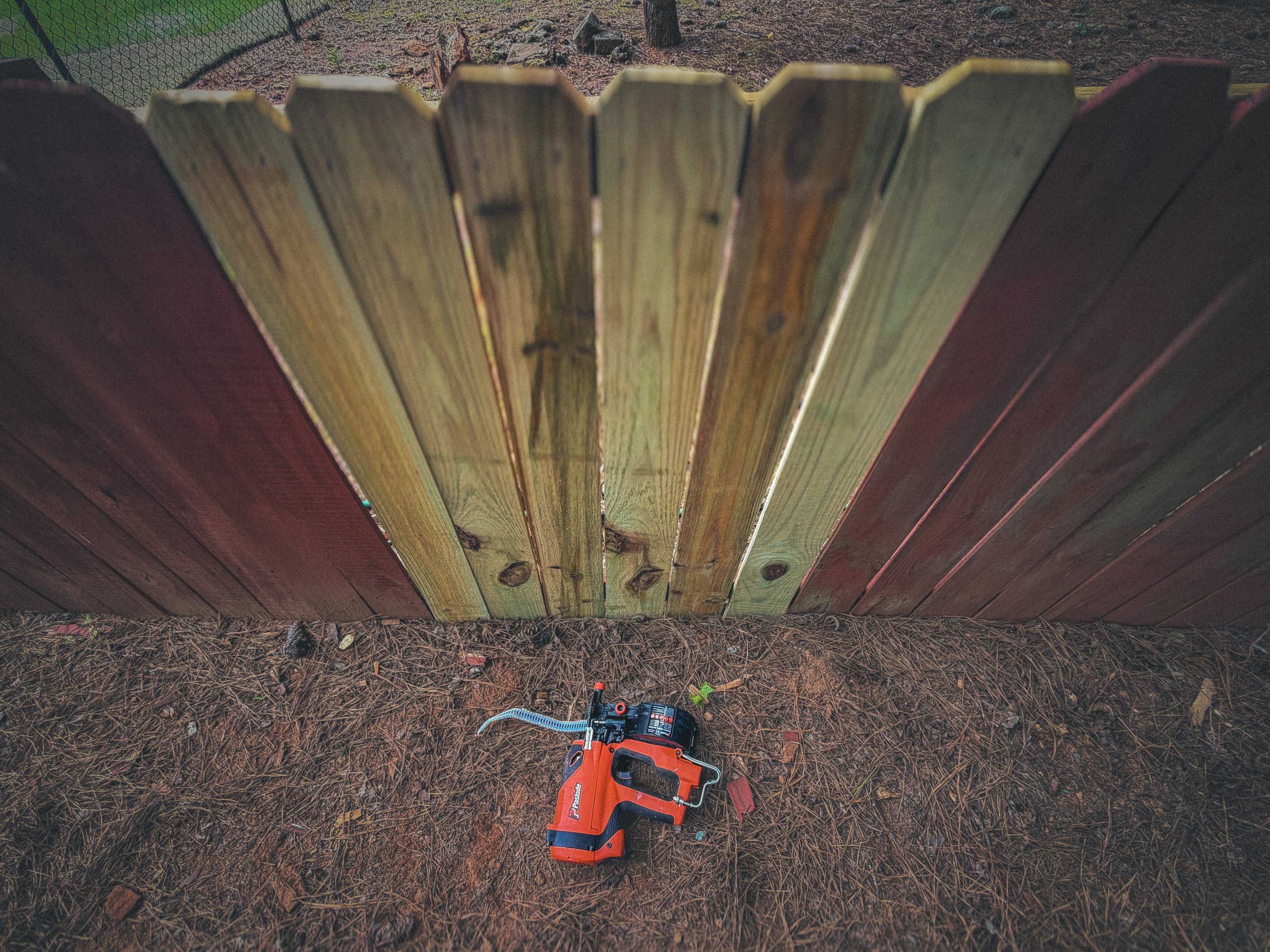 Paslode siding and fencing nailer on the ground next to new installed fence pickets for a fence repair in Watkinsville, GA