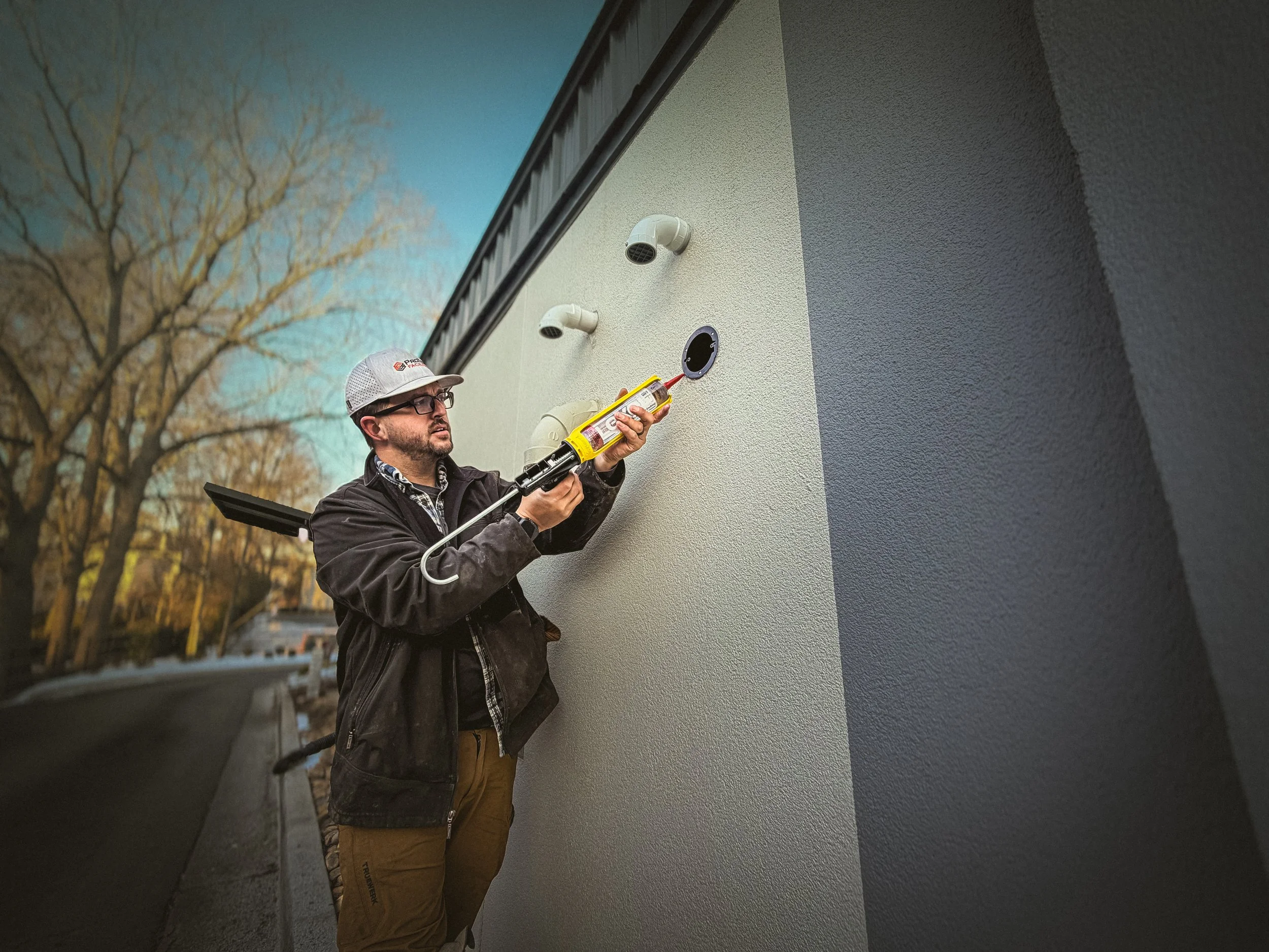 Athens, GA Handyman, repairing the exterior of a quick service restaurant, with a caulk gun loaded with Lexel in hand.