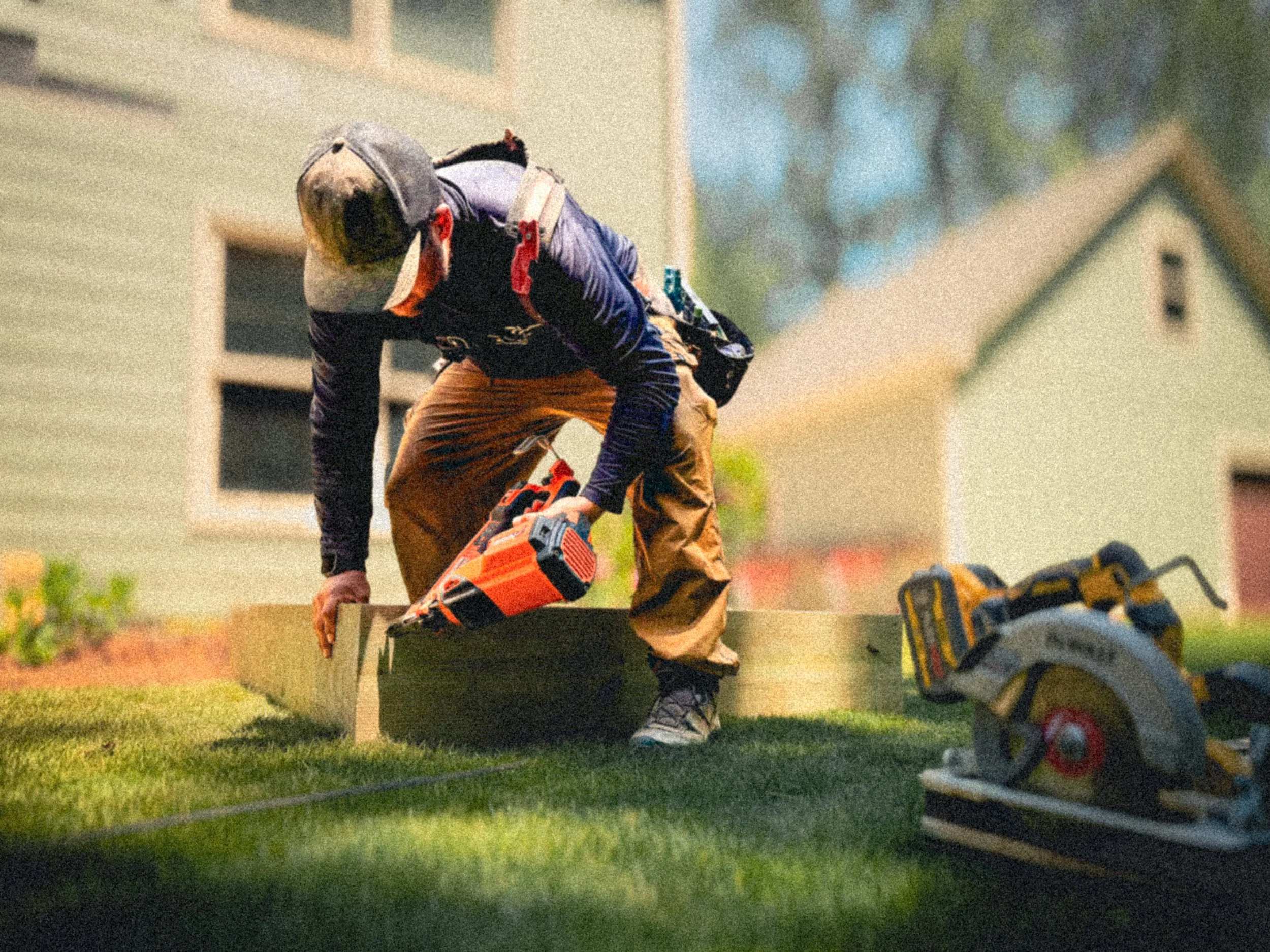 Carpenter using a paslode framing nailer to nail together the deck landing on the ground