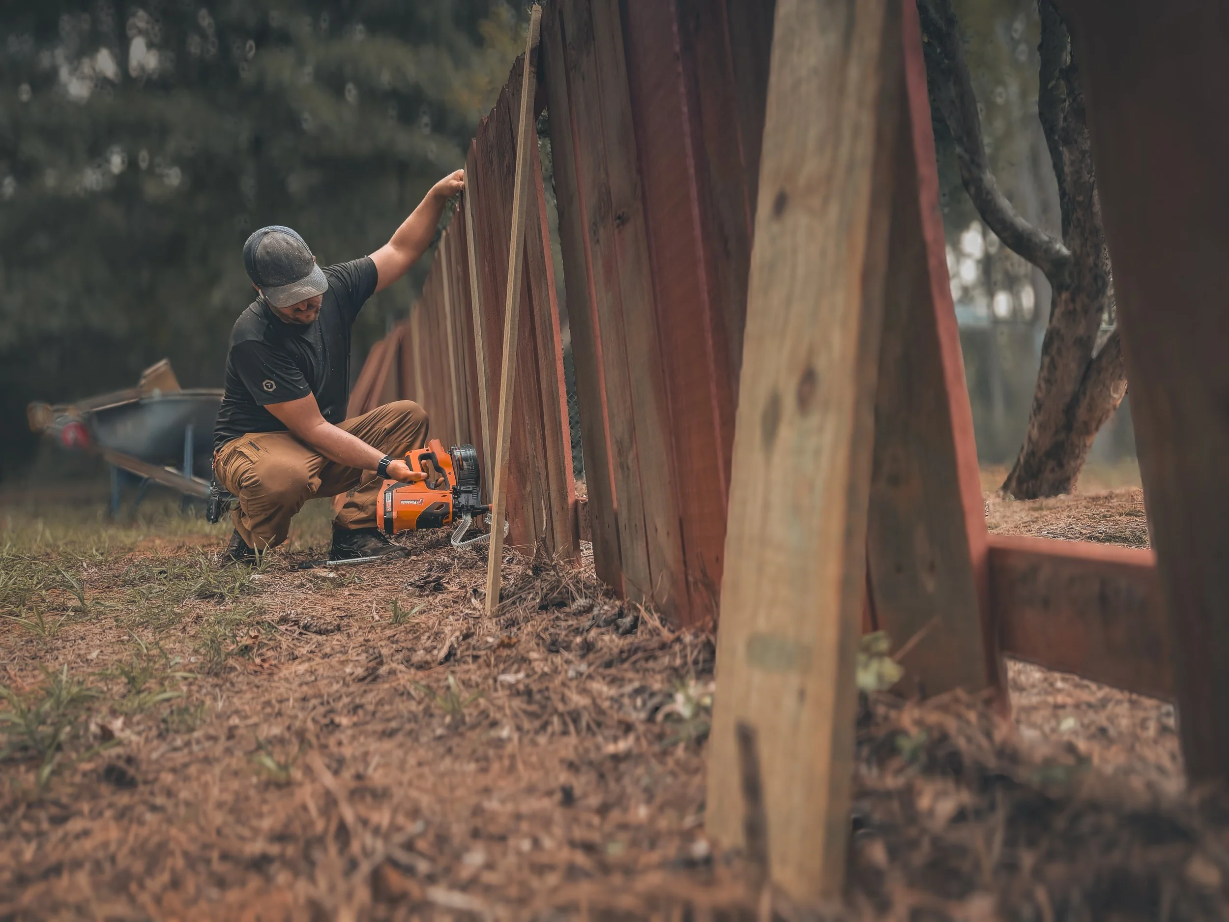 Carpenter attaching new fence pickets with a Paslode fencing nailer for a fence repair in Watkinsville, GA