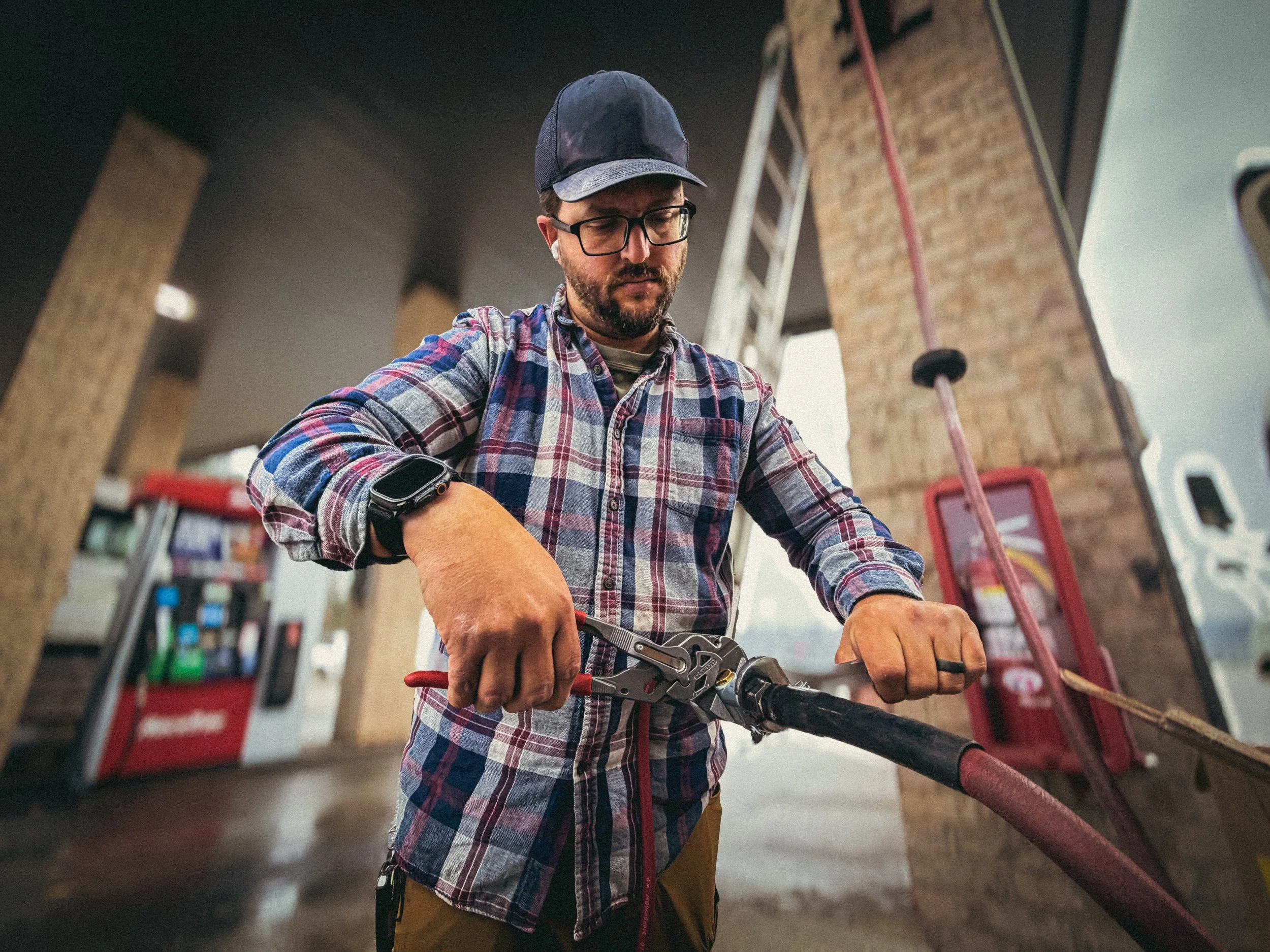 Handyman in Athens, GA repairing air hose lines at a gas station truck stop, using an adjustable wrench and Knipex plier wrench for commercial maintenance work.