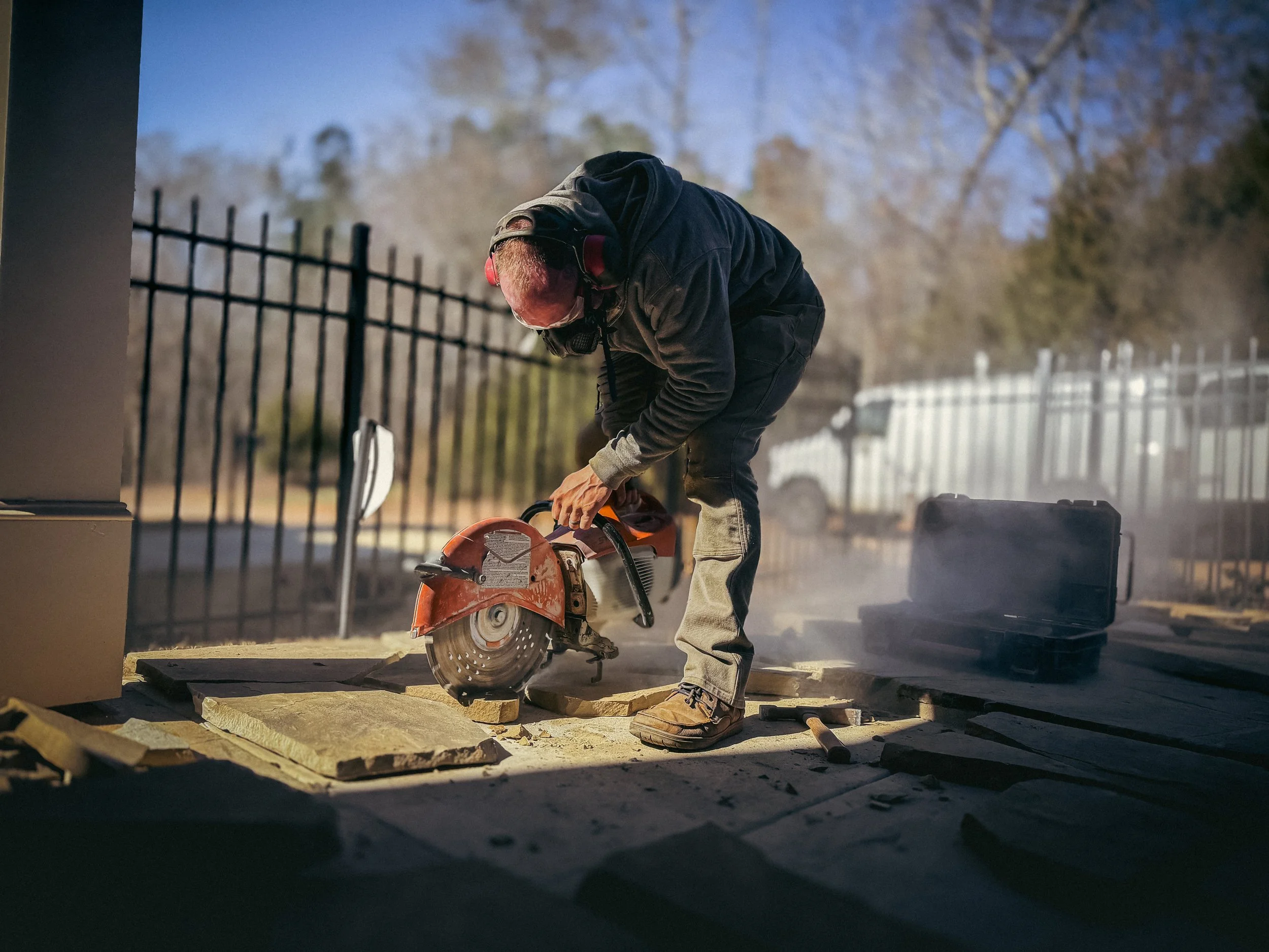 Hardscaper in Athens, GA that is using a stihl concrete saw to cut flagstone