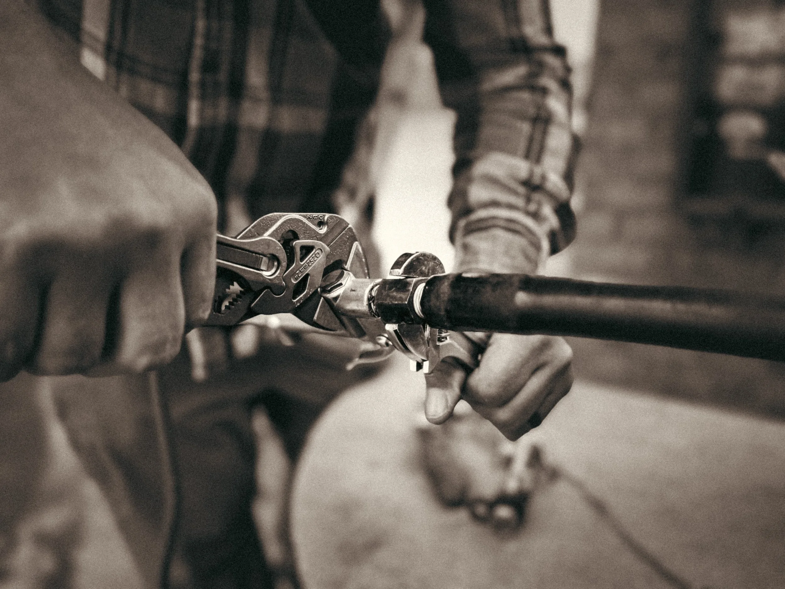 Close-up of a commercial handyman in Athens, GA repairing an air hose line at a gas station truck stop, showing wrench and pliers in use during a commercial maintenance repair.