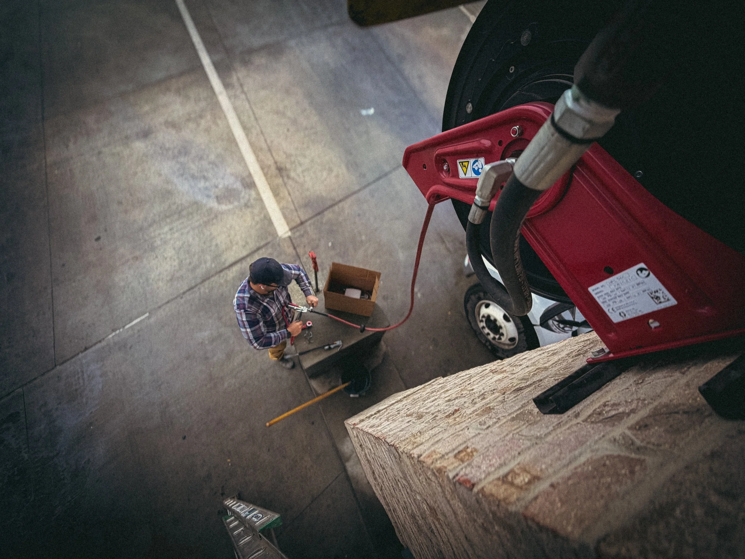 Overhead view of a commercial handyman in Athens, GA repairing an air hose at a gas station truck stop, performing commercial maintenance work at a retail fueling location.