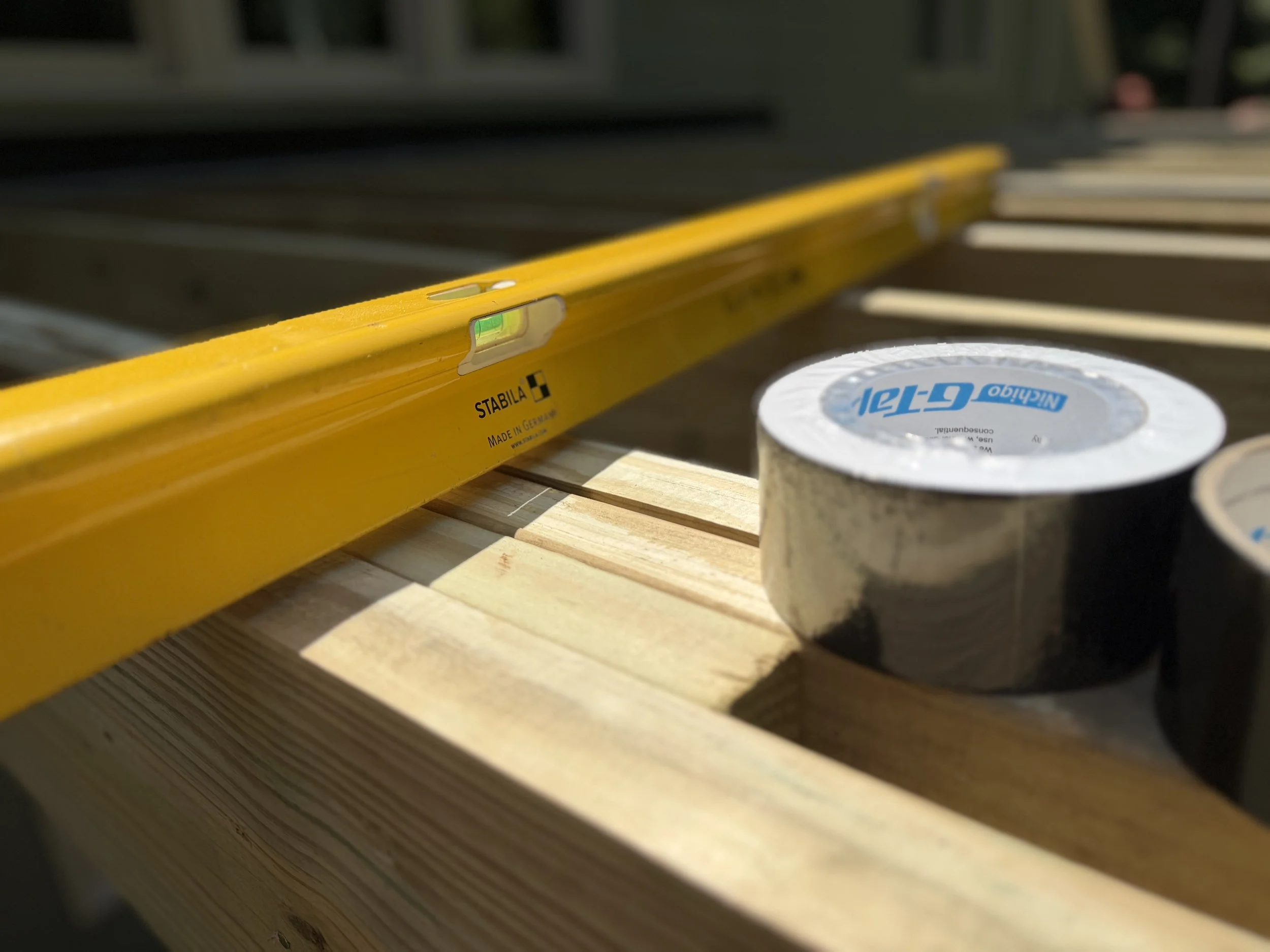 Stabilia level used to determine the flatness of deck joist, sitting next to a roll of joist tape