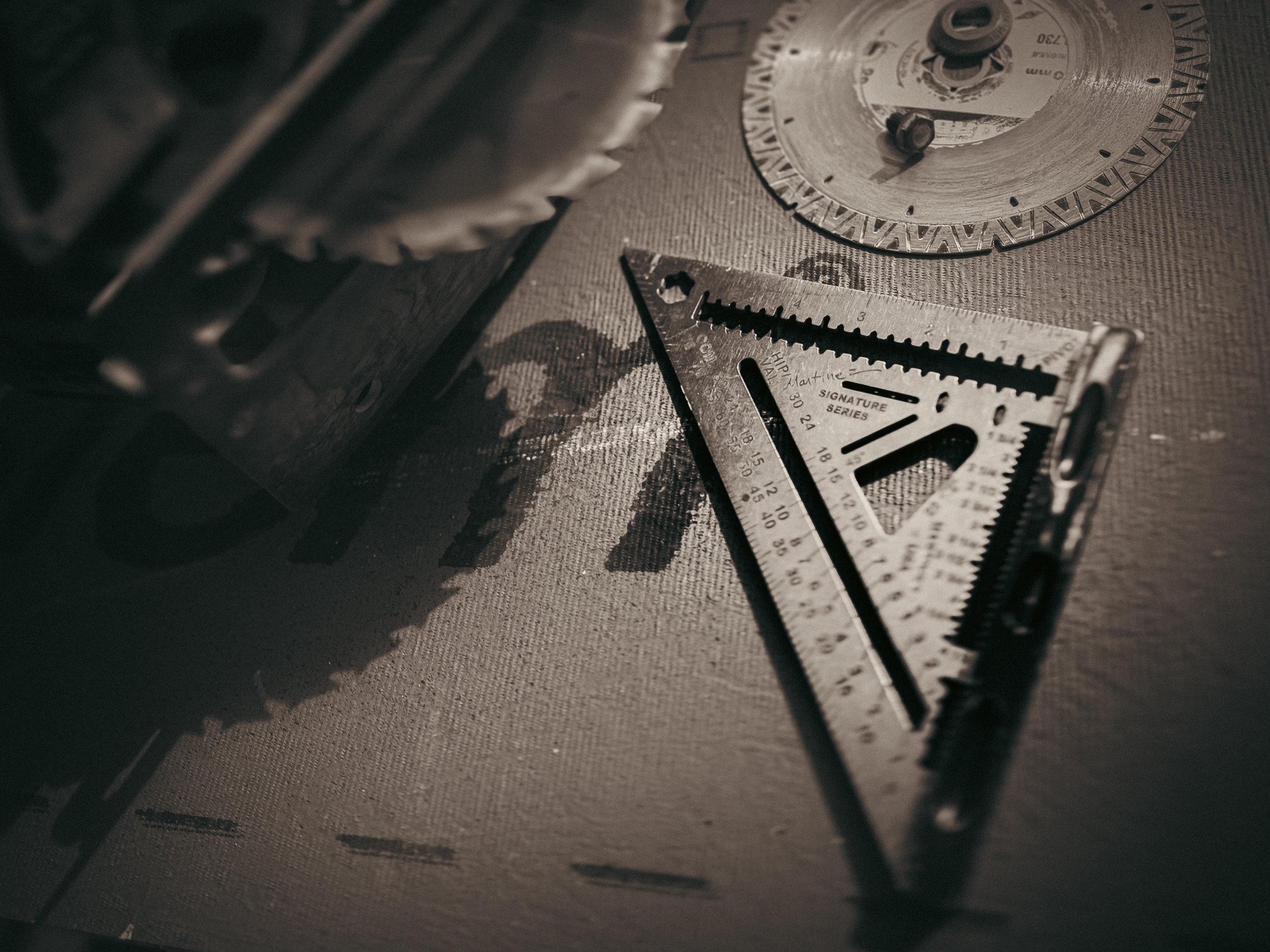 Close-up of a Martinez Tools titanium speed square and circular saw blade on a construction site in Athens, Georgia.