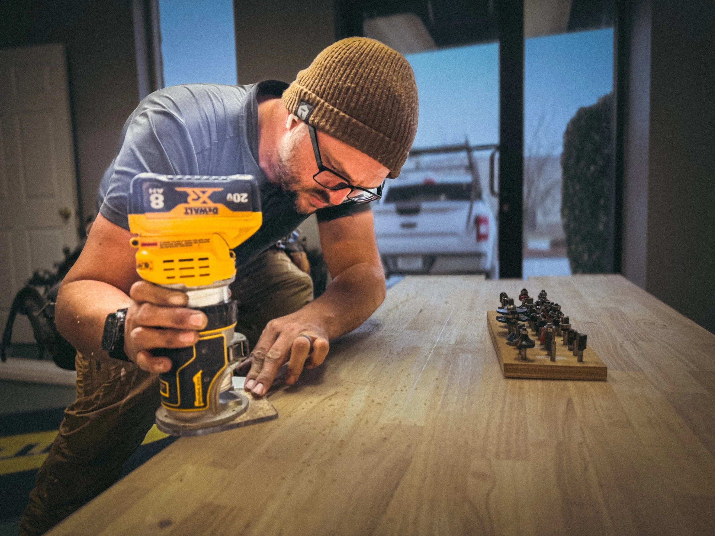 Commercial handyman in Athens, GA with a dewalt cordless router in hand and router bits within reach