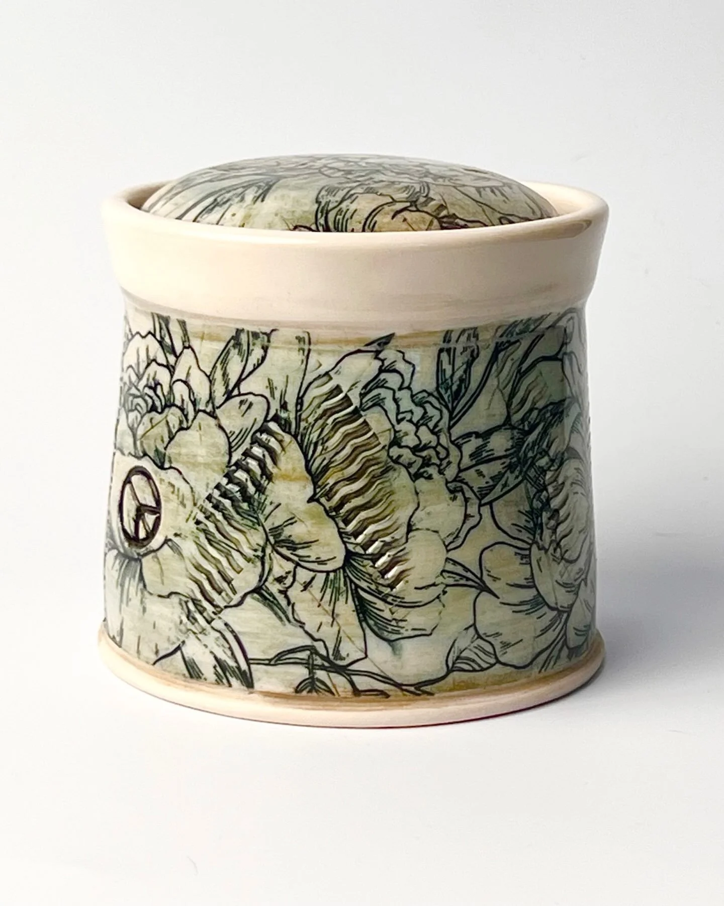 Covered jar or small urn, decorated with the Peonies underglaze transfer. The color is brushed on underglazes then I added the transfer on top. Then rolled a little texture into the surface, and used a wooden stamp for the peace sign. Clay body is La